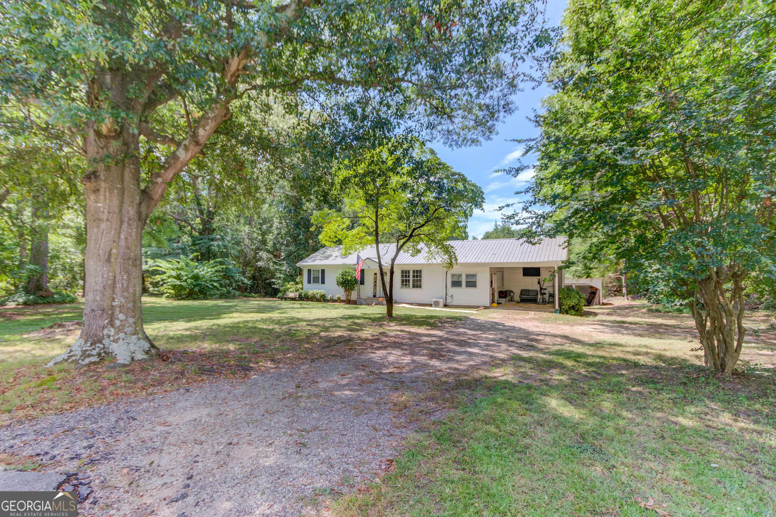 Discover the charm of country living with modern updates in this inviting ranch-style home on 1.1 level acres in Danielsville. Thoughtfully refreshed, this 3-bedroom, 1-bath home features new flooring, fresh paint, and a bright, open kitchen-perfect for both everyday living and entertaining. A spacious bonus room, currently used as the primary bedroom, offers added flexibility and comfort with its own HVAC mini-split system. Significant upgrades in 2020 include a new roof, vinyl siding, hot water heater, and updated appliances. There is also plumbing in place beneath the laundry area for a future half bath, providing an easy opportunity for expansion. Outside, enjoy the privacy of mature shade trees, a peaceful backyard ideal for gardening or play, and a partially enclosed workshop perfect for storage or hobbies. Conveniently located on Hwy 98 with quick access to Commerce, I-85, and Athens, this home blends small-town charm with everyday convenience.