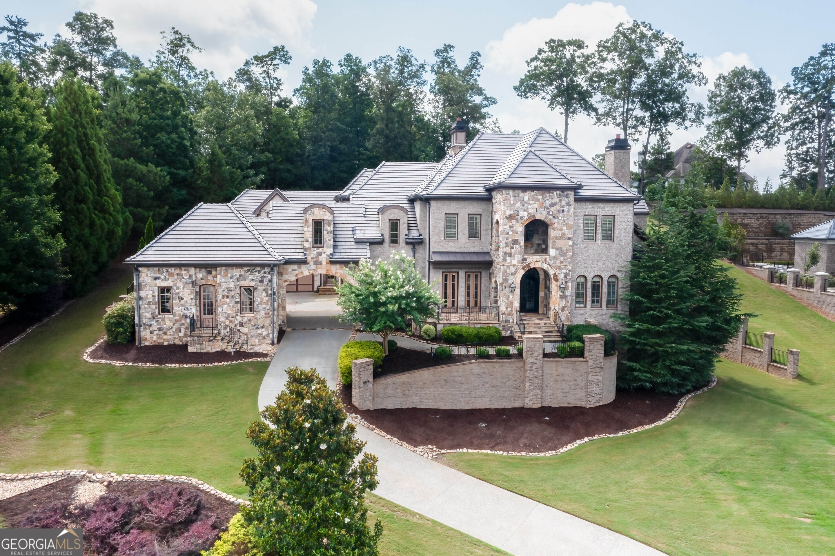 This Estate Home is located in the prestigious gated community of Grand Estates of the South. This private coveted neighborhood has only 22 lots. The gorgeous brick and stone masterpiece has 3 finished levels with a 3 stop elevator,master on the main level with fabulous master bath and oversized closet, beautiful iron entry doors, large kitchen with designer wolf and sub-zero appliances, granite counters, coffered ceilings, beautiful custom lighting throughout, hardwood floors, new plush carpet,media room, workout room, large covered patio, second kitchen in au pair suite, private backyard with room for a pool. You will feel a sense of luxury and grandeur as you enter through the porte cochere into the motor court with 4 car garages. The expansive terrace level features a media room, workout room, two bedrooms, large bathroom, gathering area and a large partially finished space for a fabulous wine cellar or library. This estate offers beautiful views from every room as you are sitting above the neighborhood from this commanding site. Warm and inviting color pallet and 5 fireplaces provide for the perfect ambience.You will love how the kitchen transitions seamlessly into the keeping room for an open yet warm feeling. This estate has professional landscaping and private gardens if you desire to grow your own spices and vegetables. Truly a remarkable place to call home.