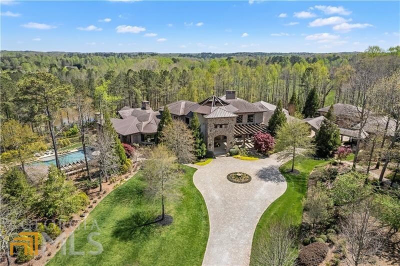 Nestled on 37+/- wooded acres, this extraordinary estate, the personal home of Hall of Fame athlete Chipper Jones, was designed to allow the considerable beauty of its location to shine. The setting is matched only by the grandeur of the house itself which takes full advantage of the propertyas natural surroundings. Passing through the gated entrance, a sweeping drive passes by a well-appointed guest house and large private lake stocked with fish ultimately arriving at the homeas impressive double height, domed entrance hall. Once inside, the open layout flows effortlessly to allow for ease of movement while enjoying sweeping views from numerous floor-to-ceiling windows. An exacting level of detail can be seen throughout the home with features including beautiful natural stone & hardwood flooring, dramatic tongue & groove and barrel cove ceiling treatments, bespoke cabinetry and designer lighting. A plush primary suite opens to a private covered patio and features a built-in floating headboard, floor-to-ceiling electric movie screen projector, massive closets with custom cabinetry and a sumptuous bath with heated floors, dual vanities, an enormous walk-in shower and free-standing soaking tub. Offering a multitude of opportunities to have fun and escape the pressures of the outside world, this private retreat includes a state-of-the-art home theatre and gaming room, sauna, kidsa playroom, wine cellar, boating shed, heated Olympic-sized pool with large cabana and outdoor dining area, plus a series of dirt bike tracks running throughout the property. In addition, world-class equestrian facilities are housed in a beautiful 4-stall stable with a 2 bed/2 bath apartment complete with kitchenette and office. Additional enviable features include a whole house generator, smart home technology and a 9-car garage.