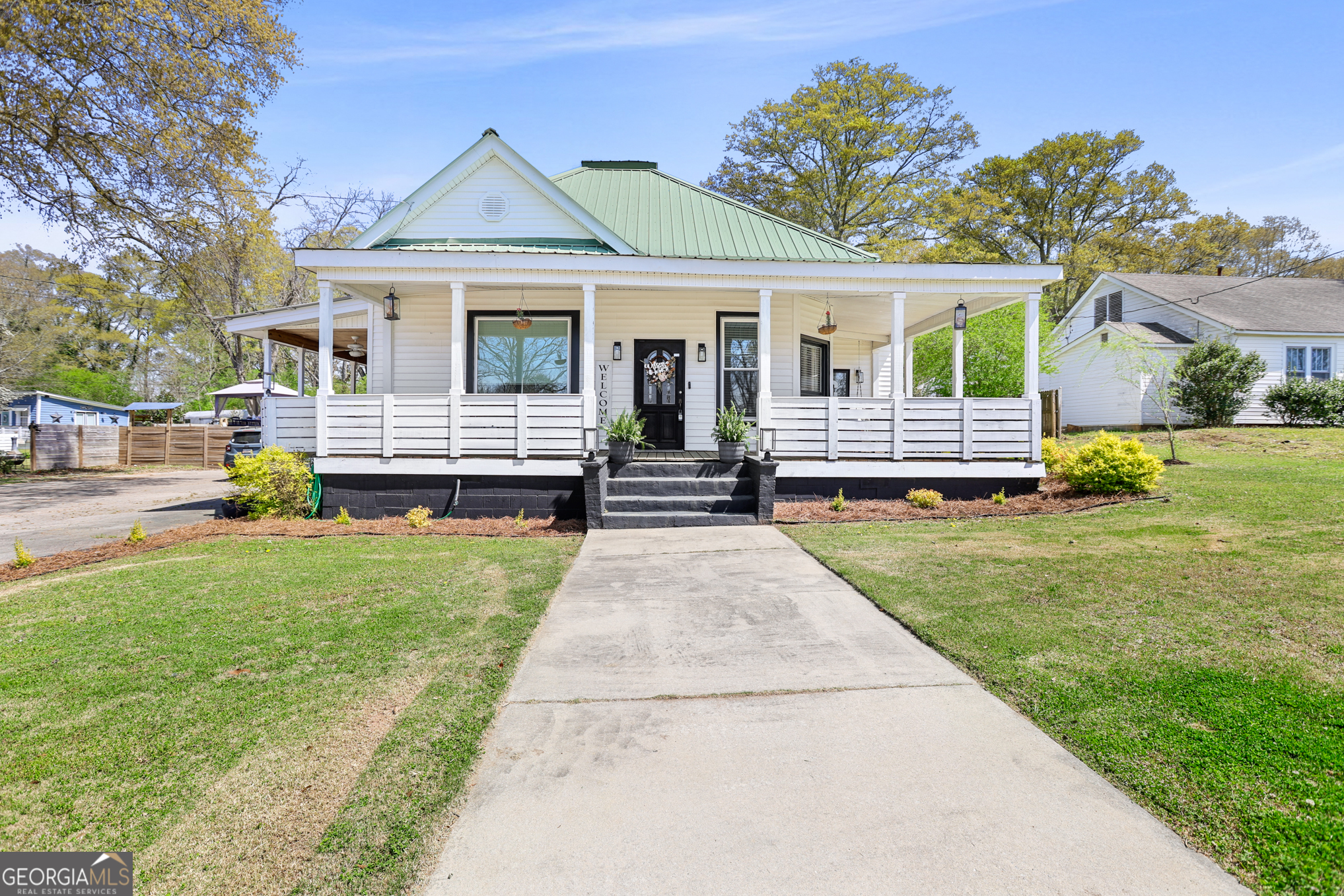 USDA 100% FINANCING TERRITORY!! POOL + NEW WINDOWS + POPCORN CEILINGS REMOVED!!!! Welcome to your beautifully modernized 1950s gem in the heart of Downtown Hogansville! This 4 bed, 2 bath ranch sits on a .6-acre lot on one of the most loved streets in town. Let's start with the wrap-around covered front porch-a full 695 square feet of charm that honestly deserves its own magazine cover. Whether you're sipping coffee or catching a sunset, it's the kind of space that turns "just a house" into a lifestyle. Inside, you'll find original hardwoods, 11+ ft ceilings, beadboard accents, and tons of natural light. The living room is warm and inviting with a brick fireplace, built-in shelving, and an additional cozy sitting area. Down the hall to the right is a spacious bedroom with exposed cedar beams, a brick hearth, and built-in shelving. Large dining room with TWO custom built-ins: one set up as a coffee bar with a wood accent wall, the other converted into a mini bar - perfect for entertaining! The kitchen blends modern updates with vintage soul - subway tile, butcher block counters, farmhouse sink, updated cabinetry (with matching dishwasher!), and a center island for prep or gathering. Off the kitchen is a huge flex room that can be a second living area, playroom, office - whatever fits your world. Through the flex room is the freshly painted primary suite with a painted brick fireplace, built-ins, barn door, and private bath with tile shower and a walk-in closet/dressing room with wood accents. You've also got two more spacious secondary bedrooms (one freshly painted!) and an updated hall bath with marble vanity and tile tub/shower combo. Wood accent mudroom leads you to the backyard - a private, fenced-in retreat with an oversized back deck, above-ground pool, and my favorite - a heated + cooled outside-access bonus space with LVP flooring and wood ceiling accents. All of this is within walking distance to all the best downtown spots like The Royal Theatre, the library, 404 Celsius, Karvelas Pizza-and just minutes to the interstate. Schedule your showing today and Come see why everyone's falling in love with Hogansville! ****PS - Do you have a friend or family member that you'd love to live next to? MLS #10575496 is also for sale next-door - this awesome family is moving together to build a new family estate so both homes are up for grabs! (A rare and golden opportunity, just saying.)****