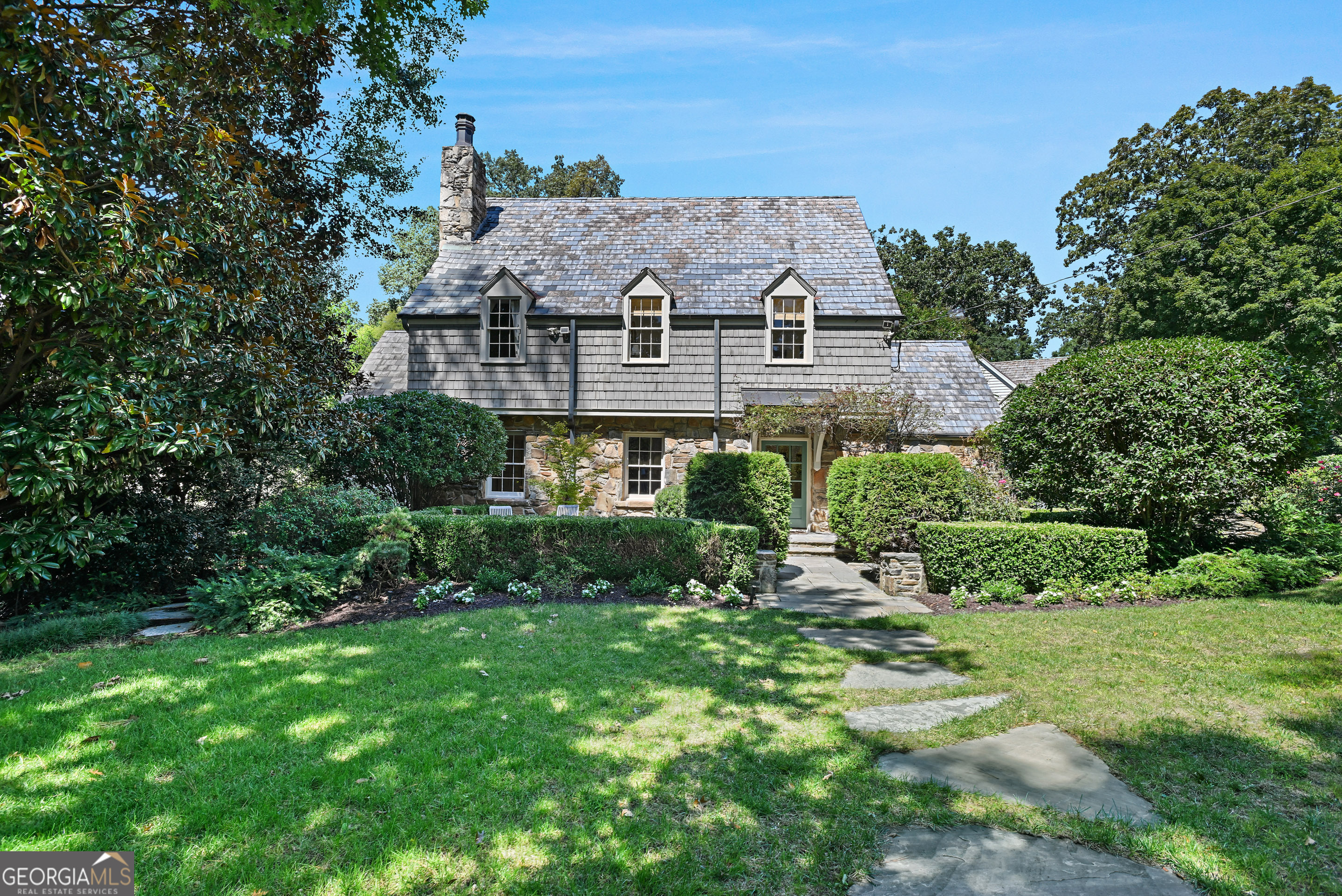 Welcome to one of the most iconic homes and curb appeal in Buckhead's beloved Garden Hills, located on Pine Tree Drive. This home pairs historic character with modern refinement. Set on a beautifully landscaped large fenced, front yard and a private backyard lot, this over 4,700 square feet home, showcases a classic slate roof, inviting cottage curb appeal, and a private backyard oasis complete with a sparkling pool and spa. Inside, light pours across hardwood floors, creating a warm, elegant ambiance throughout. The home offers several areas with fireplaces for formal dining and entertaining, in addition to four spacious bedrooms and four and a half baths, including a primary suite retreat with heated floors, freestanding soaking tub, and a walk-in shower designed for ultimate relaxation. The heart of the home is its gourmet kitchen, outfitted with Gaggenau European appliances and two expansive islands. Flowing seamlessly into an additional fireside family room with even private space for a loving pet and, an additional sunroom perfect for a yoga area or office. . Downstairs, the finished terrace level is a true extension of the lifestyle, featuring a stone-enclosed room perfect for a speakeasy, also a media room, full bathroom with steam shower and kitchenette. This open design invites gatherings that extend effortlessly to the poolside terrace. Lush gardens and multiple seating areas transform every moment into a resort-like experience. With an attached two-car garage plus additional parking, and a location just one block from the Garden Hills pool and park, walking distance to Atlanta International School, Christ the King and Garden Hills Elementary, this home embodies the best of historic charm, location, curb appeal and modern luxury. 400 Pine Tree Drive NE has been a landmark address and a lifestyle in Garden Hills.
