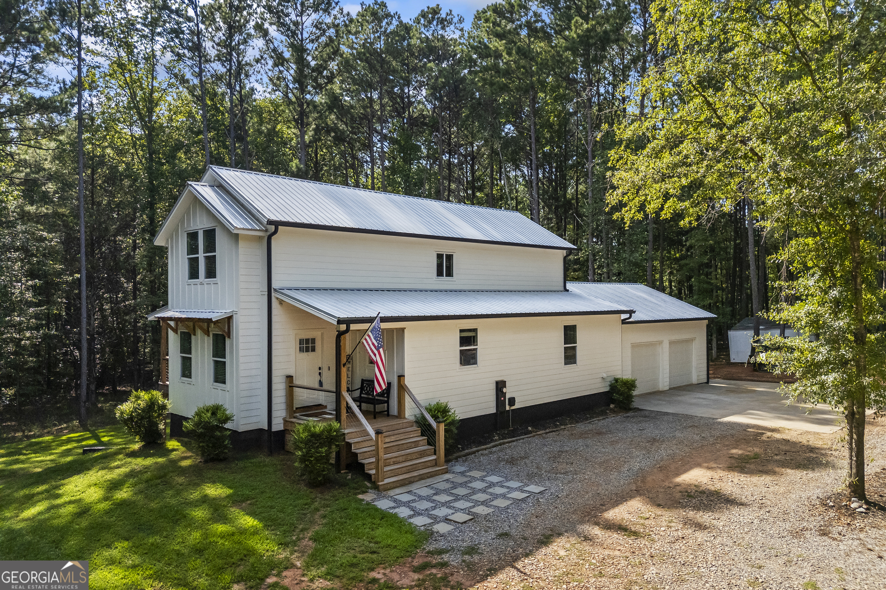Tucked away on 2.7 wooded acres yet just minutes from Highway 78, this charming home offers easy access to Monroe, Athens, and Bethlehem while providing the seclusion and space you've been looking for. Downtown Monroe is less than 3 miles away and features locally owned shops, seasonal festivals, outdoor concerts, and excellent dining. A welcoming front porch with a stained wood ceiling opens into a light-filled floor plan with stunning white oak floors throughout the main level. The living room flows seamlessly into the dining area and kitchen, designed for both everyday living and entertaining. The kitchen serves as the heart of the home with quartz countertops, custom cabinetry, floating shelves, stainless steel appliances, and a large island. Also on the main level are a half bath and a spacious mudroom/laundry room with built-in cabinetry and access to the oversized two-car garage. The owner's suite is complete with a walk-in closet with built-ins and an en-suite bath featuring double vanities and a tiled shower. Upstairs, you'll find a generous loft area or flex space, along with two oversized bedrooms, each with its own private bathroom with tiled floors and tiled tub/shower combo. The full finished basement expands the home with a kitchenette, a large living/flex area with a generous sized storage closet, a bedroom, and a full bath with a tiled shower. Step outside and enjoy the peace and privacy of your wooded surroundings from the covered deck or extended patio. With its thoughtful design, high-end finishes, and an unbeatable location close to shopping, dining, and entertainment, this home offers the best of both worlds, peaceful living with quick access to everything.