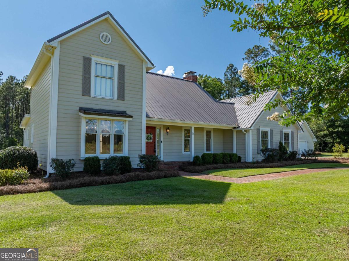 Located just minutes from Patrick's Paradise State Park, this well-maintained 3-bedroom, 2.5-bath home offers peaceful country living on 2 beautifully landscaped acres. A crepe myrtle-lined driveway leads to a welcoming brick walkway and cozy front porch. Inside, you'll find hardwood floors, a beautiful staircase, and a spacious layout including a formal dining room, modern farmhouse kitchen with movable island, and a breakfast nook overlooking the scenic backyard. The family room features built-ins, a fireplace, and access to a covered back porch-perfect for relaxing. Upstairs includes the primary suite, two guest bedrooms, and a second full bath. A detached shop with a roll-up door provides excellent storage or workspace, A chicken coop and a fire pit area. Built in 1980 with 1,934 sq ft, this home is clean, inviting, and full of charm.