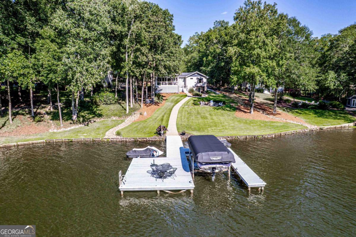 Beautifully renovated, furnished & move-in ready, this Lake Oconee home checks all the boxes! Designed for comfort, style, & fun on the water, this open concept layout is filled with natural light & sweeping lake views. The stunning kitchen anchors the main level, which also features the primary suite & a guest ensuite. The terrace level offers an additional bedroom & ensuite bath, a great flex space perfect for a bunk room, fitness, or art studio, plus a spacious rec. room & second kitchen. Outdoors, you'll love the huge covered porch, firepit, & level lakeside lot. The dock (2019) plus a brand-new boat cover mean you're ready to hit the water right away! A detached oversized 2-car garage with workshop & ample storage provide convenience & functionality. Modern upgrades include smart lighting, climate control, & security-all managed from your phone. Residents enjoy exclusive access to a private beach, pavilion, playground, & boat launch. Whether you're seeking a full-time lake retreat, weekend getaway, or investment property (short-term rental permitted with county approval), this home delivers! Close to restaurants, shopping, & Lake Oconee's favorite destinations, this property blends privacy, natural beauty, & modern comfort-ready for you to relax, entertain, & make lifelong memories.