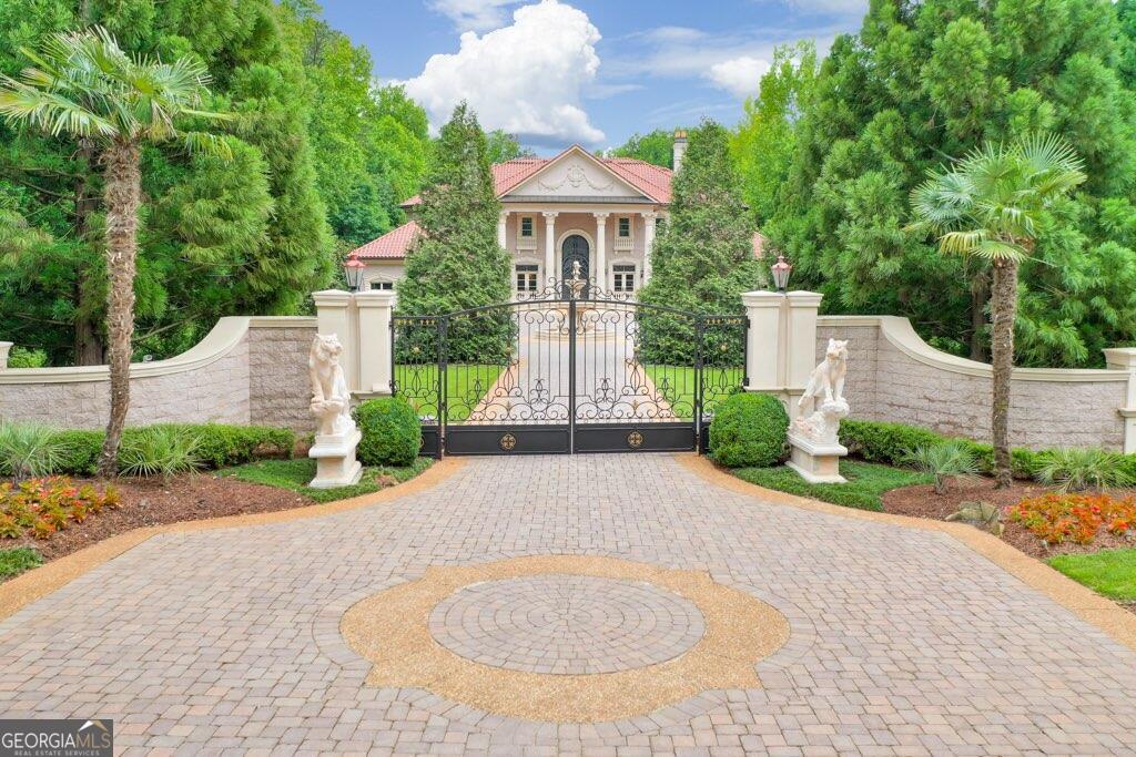 Exquisite gated estate on 2.2 acres in top Walton school district in low tax Cobb County showcasing the finest finishes, stonework, unmatched quality, and artisanship from all around the world. The dramatic hand carved tigers meet you as you drive through the gates surrounded by the lush landscaping and into the full circle motor court bordering a custom hand carved stone swan limestone fountain and garage housing for four vehicles. Dramatic castle-entry front doors welcome you with grandeur. Baccarat and Murano lighting line the interior as you view the stunning baroque double spiral staircase with hand-forged Cantara ironwork, marble floors with imported Rossini mediations, gilded trim and hand laid 24 carat gold leafed domes. Arched cantara doors lead to private entry into the lush Primary suite on main with unbelievable spa bath - marble and hand laid gold mosaic tiles, stunning gold Sherle Wagner fixtures. Three separate kitchens with Viking and subZero appliances can be found throughout the estate. Terrace level features -gym with redwood sauna, Cantara wine cellar, and home theater featuring legendary Klipsch sound system, precise lighting and acoustically rich fabrics providing for unforgettable private screenings. The finest of imported mosaics were meticulously hand-applied by Fantini Mosaici's team of artisans to create the breath taking pool and spa, only otherwise found within the finest Italian luxury villas and resorts. Separate pool house includes a full kitchen and guest suite. Lighted Deco Turf tennis court behind the pool house, the same surface as used in the US Open. Lacey champion hand tufted wool carpets (also seen in the White House) found in various rooms throughout the house. 6 fireplaces, all custom with unique imported finishes from around the world. Additional features include an elevator servicing all three levels and custom closets designed to complement each room's unique style, ensuring both convenience and luxury at every turn.