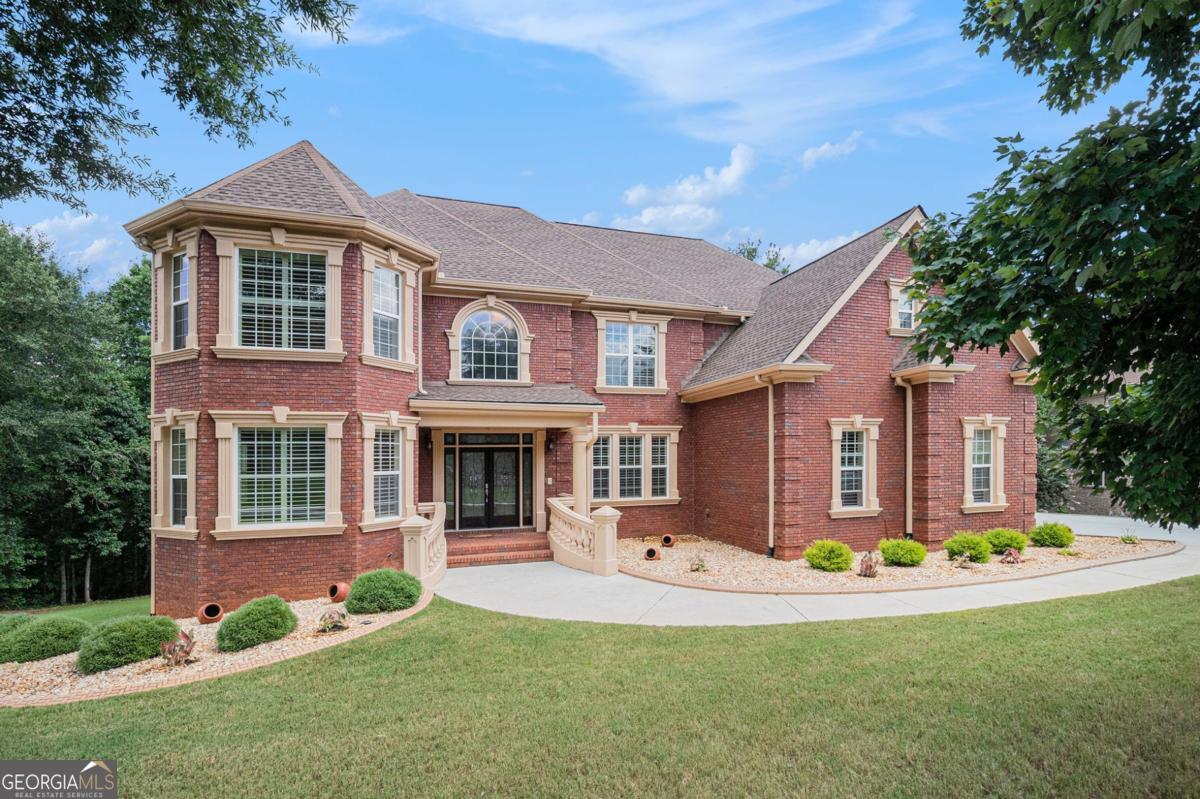 Welcome to room-for-everyone living in prestigious Madison Creek! This elegant, custom all-brick estate rests on a rare 1.78-acre wooded homesite and delivers the space, flexibility, and privacy today's buyers crave. A graceful approach leads to a dramatic two-story foyer opening to oversized formal and family spaces framed by rich millwork, soaring ceilings, and classic crown/dentil molding that speak to true craftsmanship. The gourmet kitchen anchors the main level with granite countertops, center island, double ovens, stainless-steel appliances (refrigerator stays), abundant cabinetry, and a bright breakfast area that flows to a large entertaining deck overlooking serene, treed grounds-perfect for gatherings. Three fully finished levels create outstanding multi-generational options, guest/in-law living, or potential rental income. Total of 8 bedrooms and 5 full baths across the home. All-brick construction, double rear decks, side-entry 3-car garage, and generous outdoor play/garden space set this property apart in Rockdale County. Terrace (lower) level: 3 bedrooms, full bath, fresh paint, carpet, kitchenette, laundry room, abundant storage, theatre/media room, and utility space with tankless water heaters-ideal for long-term guests or an income suite. Main level: hardwood floors; tiled baths; fresh paint; formal dining & formal living; fireside family room; main level en-suite bedroom/bath for aging in place; smart Nest thermostat; Vivint security system & cameras remain. Upstairs: enter from kitchen or main foyer stair. Hardwood on stairs; luxury vinyl in bedrooms; tiled baths; 4 bedrooms/3 baths including a generous primary retreat with private sitting room, convenience refrigerator, access to an upper deck, large walk-in closet, and oversized shower. Upstairs laundry. Recent service/maintenance notes (per seller): New roof installed in 2022; Move-in ready with room to personalize. Ready for space and flexibility on acreage in Conyers? Schedule your showing today!