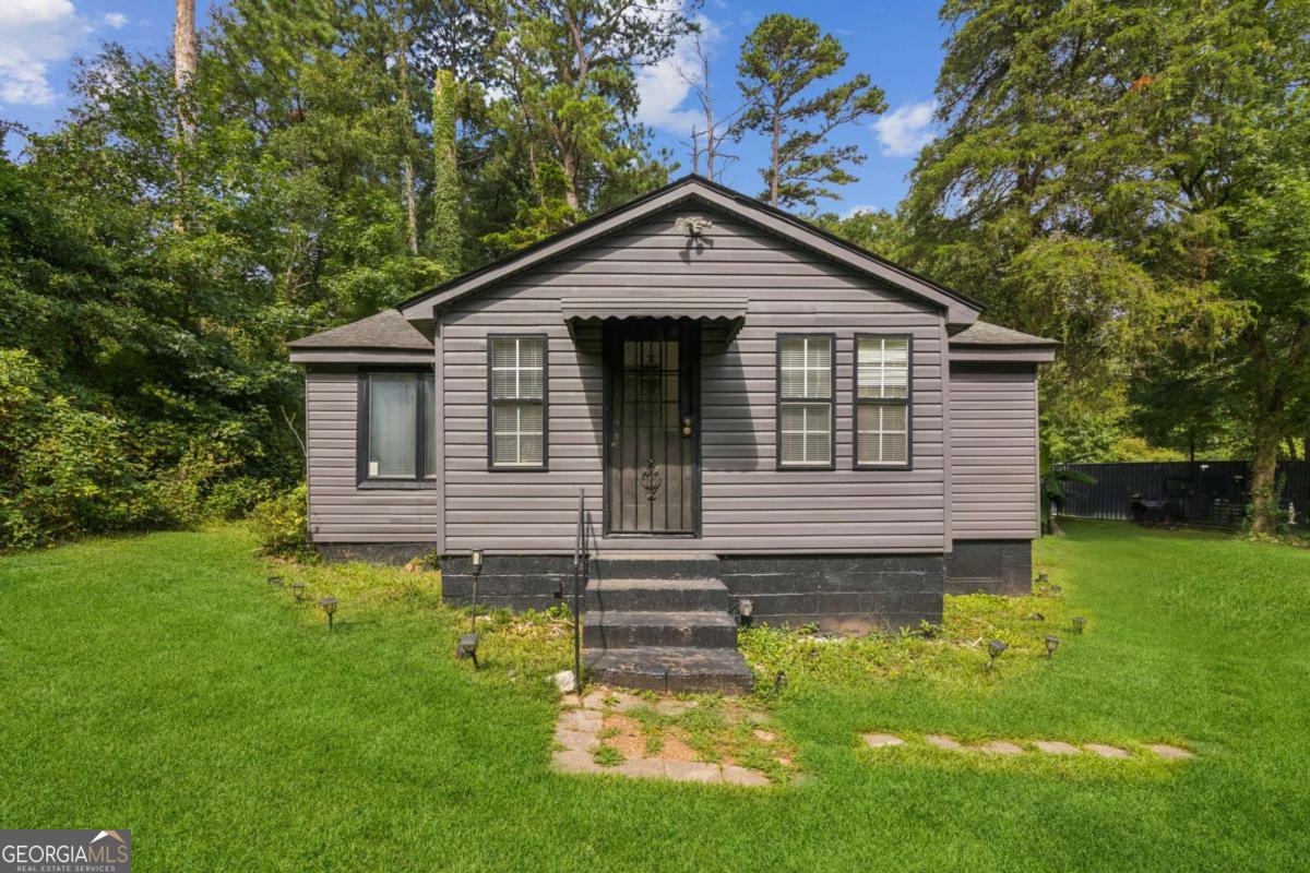 Incredibly unique one bedroom bungalow with bonus shipping container living space, AND a two room underground bunker/fallout shelter! Don't let the unassuming facade fool you, this is a once in a lifetime opportunity to own a fully equipped one-acre property in Fairburn - perfect for those seeking disaster preparedness, off-grid potential, or a one-of-a-kind lifestyle retreat. Step inside where a completely renovated open floor plan greets you with a cozy separate dining/sunroom and central family room with vaulted ceiling, exposed beams, and glass wall with accent lighting. Charming kitchen open to the family room features rich wood cabinetry, stylish tile backsplash, and stainless steel appliances. The oversized primary suite offers new carpet and a custom ensuite bath with upgraded flooring. Outside, you will discover a bonus shipping container converted into the coolest "man cave" with kitchenette, and extra storage in the rear. Two-room underground bunker/fallout shelter has living and storage areas for the ultimate in long-term preparedness or creative use. Expansive back deck has tons of space to enjoy the great outdoors. Additional features include RV connections on site, detached deer stand storage shed, ample parking, and endless potential to expand. This distinctive property surrounded by mature dogwood trees combines comfort, self-sufficiency, and unlimited character. Property sold AS-IS.