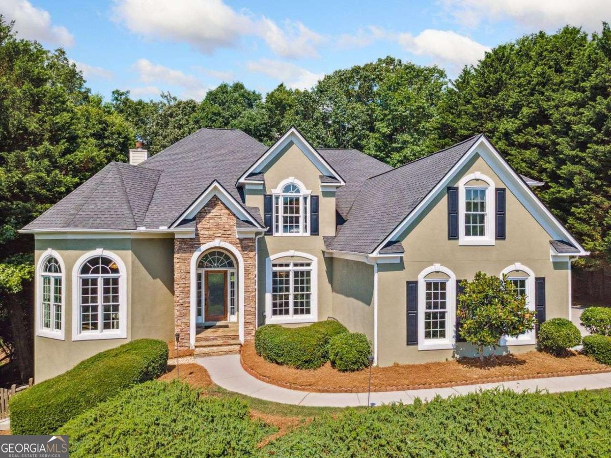 Perched on a scenic hill, this beautifully appointed 5-bedroom, 4.5 bathroom home offers privacy and breathtaking views with the east-facing sunrises in the front and sunsets from the west-facing back. Inside, enjoy refinished hardwood floors and freshly painted walls. The kitchen features stainless-steel appliances, including a smart double oven with air fryer, a whisper-quiet dishwasher, and a double-door refrigerator. Heated tile floors in the laundry room and half bath elevate the space with a touch of luxury, complementing the high-end upgrades, including a floating sink, color-changing LED lighting, and a custom-designed mirror. Upstairs, the primary suite showcases a bold Gatsby-inspired wallpaper accent wall and custom closet. Luxurious finishes continue in the primary bath, where a spacious tiled walk-in shower with a rain showerhead meets updated tile flooring and custom countertops. Three additional upstairs bathrooms have been updated with "Calacatta Wow" quartz countertops and auto-sensor shower fans. Offering incredible potential, the unfinished basement is fully studded, roughed-in for a full bath, and features walk-out access. The washer/dryer, all major kitchen appliances, 65" TV, grill, and patio furniture remain with the home. Additional highlights include dual Google Nest systems, newer AC units, new exterior shutters, and new front windows, re-tiled fireplace with oak mantel, large level parking pad, and an oversized three-car garage. The back deck creates a tranquil retreat for relaxing and entertaining, all while overlooking a private, wooded yard that's flat, fenced, and full of charm with easy access in and out through your three gates on each side of the home, as well as, the back. Just beyond your back gate, you will find a densely wooded forest perfect for privacy and exploring alike. Nearly every detail has been thoughtfully upgraded, including refinished stair rails, new door hardware, automated exterior lighting, and chic chandeliers with dimmers. This vibrant swim and tennis community offers top-tier amenities, including a kids' splash pool, a serene adults-only pool, playground, baseball/sports field, six tennis courts, basketball court, pickleball courts, fishing ponds, and a competitive swim team. Scenic walking trails wind throughout the neighborhood, connecting directly to the Chattahoochee National Forest, Bowmans Island, and nearby Haw Creek Elementary and Lakeside Middle School. Enjoy easy access to Northside Hospital, parks, shops and restaurants -- highlighted by the newly developed Cumming City Center just minutes away.