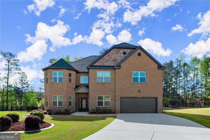 Welcome to 404 Prague Way, an exquisite residence nestled in the heart of Hampton, Georgia within the highly sought after Crystal Lake Golf and Country Club! This expansive 5,145-square-foot home, built in 2021, offers six generously sized bedrooms and 4.5 bathrooms (Owner's Room on Main Level), providing ample space for both relaxation and entertainment. Upon entering, you're greeted by a grand two-story foyer that sets the tone for the rest of the home's refined interior. The open-concept main floor flows effortlessly from the formal dining area-perfect for hosting elegant dinners-to the spacious living room, highlighted by soaring ceilings, oversized windows, and a cozy fireplace that anchors the space. The gourmet kitchen is a chef's dream, complete with granite countertops, stainless steel appliances, an island with additional storage, tile backsplash, and walk-in pantry. Adjacent is a breakfast nook that opens to the family room, offering seamless connectivity for everyday living. The main level also features a convenient guest suite with a private full bath, ideal for multigenerational living, a home gym, or visiting family. Located on the main level, the luxurious owner's suite offers a private sanctuary complete with a separate sitting area, tray ceilings, a massive walk-in closet, and it's own washer/dryer. The en-suite bathroom evokes spa-like tranquility with dual vanities, a deep soaking tub, and a handicap accessible shower. Each of the additional guest bedrooms is thoughtfully designed, boasting generous proportions, ample closet space, and easy access to well-appointed bathrooms, including two Jack-and-Jill setups perfect for siblings or guests. A large loft area upstairs provides extra living space that can be used as a media room, playroom, or second family room. Elegant finishes such as crown molding, upgraded lighting fixtures, and luxury engineered hardwood plank flooring elevate the home's aesthetic and create a warm, welcoming ambiance. The exterior of this distinguished property is equally impressive. Situated on a meticulously landscaped lot, the home features a stately brick facade complemented by tasteful accents and charming architectural details. A two-car garage provides secure parking, while the extended driveway offers additional space for guests. The backyard is a true retreat, offering a large enclosed patio perfect for grilling and outdoor dining. The surrounding greenery, well-manicured lawn, and privacy fencing make it a peaceful space to unwind or entertain. Located in a quiet cul-de-sac, 404 Prague Way offers residents a harmonious blend of suburban tranquility and urban convenience. The area is known for its welcoming community, well-kept surroundings, and proximity to top-rated schools, making it an ideal setting for families. Commuters will appreciate quick access to I-75, while shopping, dining, and entertainment options are just minutes away. Nearby parks and recreational facilities, including golf courses and nature trails, offer abundant opportunities for outdoor enjoyment. Schedule your showing TODAY!