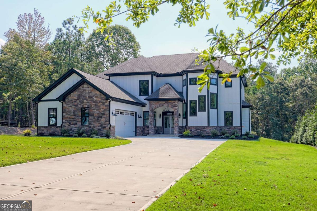 BRAND NEW, 4 bed, 3.5 bath, 3,896 sq ft luxury craftsman perfectly positioned on a level 1.39-acre LAKE LANIER LOT. Bring your fishing pole and kayak and come enjoy all Lake Lanier has to offer, also in addition, Van Pugh boat ramp less than 5 minutes away! Pull down the quiet street of Snelling Mill Road to a perfectly manicured yard and you will instantly notice a stunning home with stone & board and batten exterior, arched stone entryway, gorgeous firepit area, and the perfectly flag stoned back porch leading to MULTIPLE PATHS TO LAKE LANIER. Inside you will find tons of natural light and wonderful finishes including: an upgraded lighting package, stacked stone fireplace, beams and wood detail throughout, stunning tile showers & baths, luxury vinyl flooring and a well thought out floor plan with tons of storage! The home also includes chef's kitchen with stainless appliances, custom cabinetry and formal dining. This exquisite LAKE LANIER home is the perfect blend of luxury & lake living in the heart of Flowery Branch!