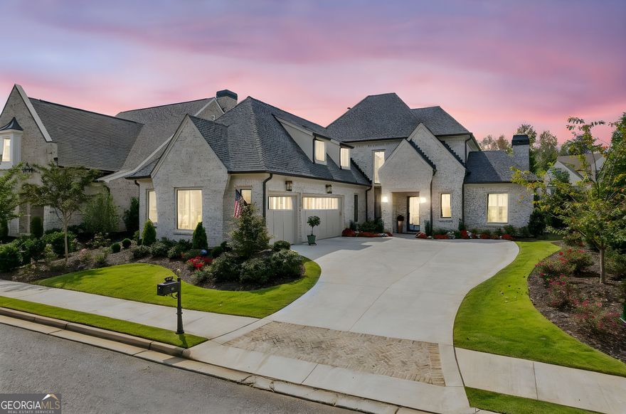 Exceptional opportunity in The Manor Golf & Country Club, nestled within the exclusive Manor Cottages enclave - this 2024-built home by Santoro Signature Homes showcases curated designer selections and sophisticated finishes throughout its 3750 square feet of elegant living space. With 4 bedrooms, 4 full bathrooms, and 1 half bathroom, the thoughtfully designed floor plan offers a seamless blend of open concept living and private retreats. The Main level features an open Kitchen with top-of-the-line Wolf and Sub-Zero appliances, leathered stone countertops, custom range hood, large island, breakfast bar and service pantry. The Kitchen is flanked by a vaulted Great Room with a gorgeous linear gas fireplace, exposed beams and a wall of windows overlooking a magnificent, show-stopping waterfall & pond in the backyard. The Kitchen also opens to an oversized Dining area with a custom-built bar with antiqued mirror backing, custom shelving and a beverage refrigerator. Sliding glass doors lead from the Dining area to a covered wood-burning fireside Veranda; and a serene saltwater, heated Pool & Spa. The luxurious main level Owner's Suite features a stunning, spa-like bathroom with large shower, double vanities, additional heater and a spacious walk-in closet with custom built-ins. Additionally, the main-level offers a vaulted, custom trimmed Office with private access to the veranda and pool area; a showstopping Powder Room with underlit, floating vanity; and an oversized Laundry Room & Mud Room area with custom shelving galore. The Upstairs features three private, spacious Bedroom Suites, each with a walk-in closet and en-suite bathroom. There is also a Flex/Bonus room on the 2nd level of the home that could be used as an office, exercise room or library. This home's Three Car Garage features an epoxy painted floor and a surround of wainscot trim moulding. The exquisite craftmanship and extraordinary level of finishes throughout this home are unparalleled - from the top-of-the-line hardware & elegant Brizo faucets to the spectacular light fixtures; from the trim package in every room to the dramatic pops of designer wallpaper; from the custom shelving in every closet to the tile work in every bathroom. This home is impeccable from top to bottom.  The home also offers an incredible amount of Storage space. The Manor is gated and has superlative amenities including indoor and outdoor pools, indoor and outdoor tennis courts & pickleball courts, fitness center, two Clubhouses, 18-hole Tom Watson designed golf course, and sidewalks throughout. Phenomenal school district. Close to shopping and easy access to GA 400.