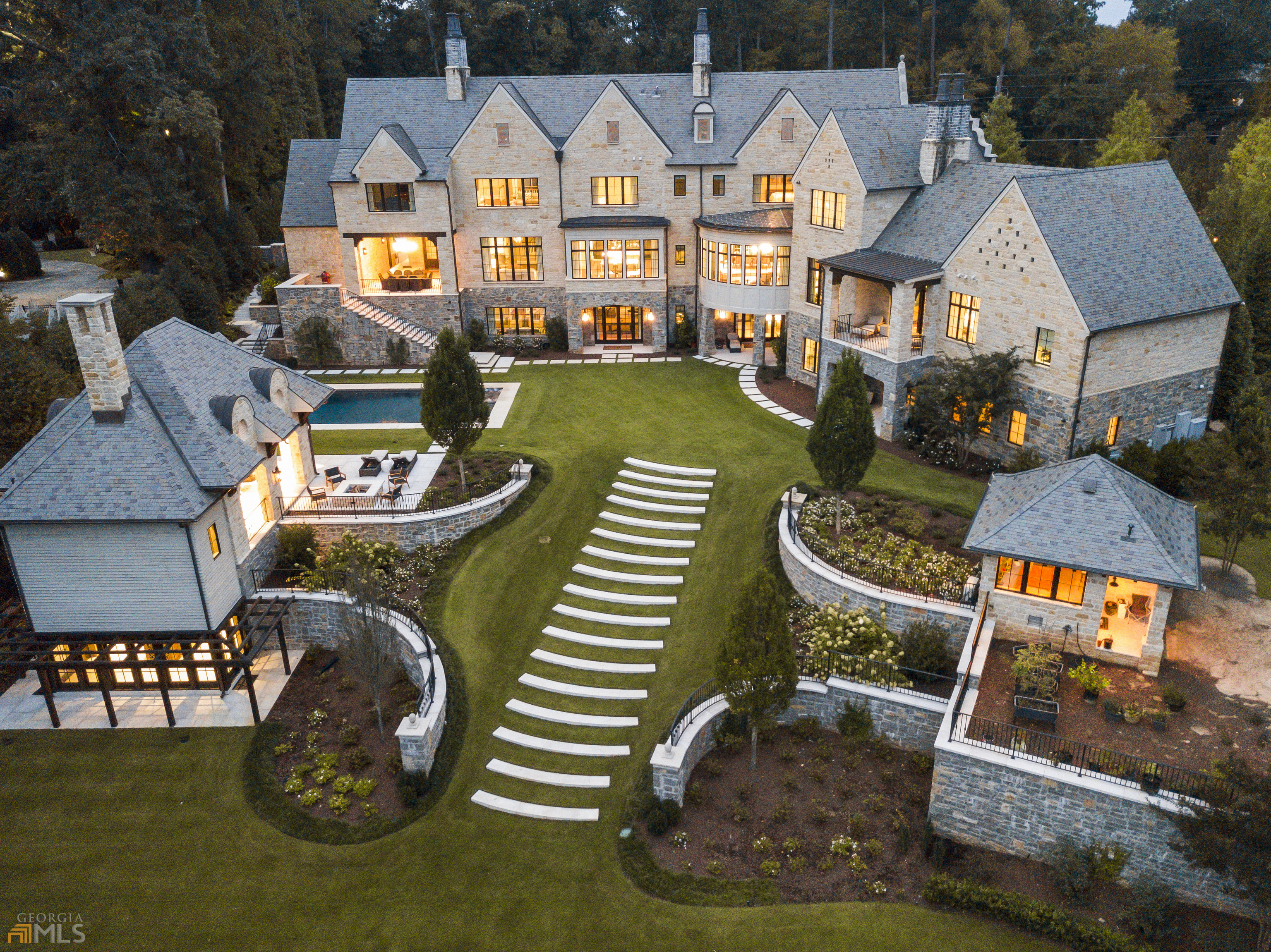 Behind a massive gate is spectacular residence constructed of stone, limestone and slate on almost two acres of breathtaking grounds.   Harrison Design was the Principle design firm for the entire property including the landscape design, and all interior finishes and furnishings. Located in a very private estate neighborhood in North Buckhead (30327) but technically in Sandy Springs. This exceptional neighborhood is extremely desirable for many reasons including privacy with 2 acre minimum lot sizes. The property is 10 minutes from Buckhead shopping, restaurants and great schools, both public and private. Current owners moved in 2020 and the house feels like new construction with the latest in finishes. Timeless in design and transitional in style. It is rare to find a residence with 12' ceilings on the main and terrace level with wide plank Walnut floors, tons of windows that capture property views in the front and back of the property. Breathtaking kitchen, breakfast, family and loggia have views of the front of the property and the back by the pool. Double quartzite islands with custom cabinetry by Kingdom. Wall of glass at the sink views of the gardens and the property. Loggia with fireplace outside of family room overlooks the pool. Wine bar, SubZero, Wolf, double dishwashers, coffee stations and views galore in the front gardens and back. Mature trees and landscape all around the property make the property feel like a completely private retreat. Upstairs has 5 bedrooms that include a guest apartment and upstairs living room and laundry. The dream terrace level is all glass and triple sets of doors out to the pool. It is like another whole level of gorgeous living spaces. Add a golf simulator instead of the pool table! This level has the best bar with the works including a beer tap. The new custom glass and stone wine room next to the bar is a beautiful viewing feature on this level. Exercise in the gym with yoga room, steam and sauna and then sit outside on the patio or go for a swim. New pool house with bar, wood burning stone fireplace and outdoor fire pit, 2 baths, guest space and retractable screens. New conditioned potting room with half bath for the gardener. Open living spaces flow smoothly throughout the house with the primary suite and study off to the left with patio that overlooks the property and two sets of motorized blinds for light control. This home is turn-key ready. Control4 automated smart home with lighting, music, and security. Elevator. Whole house generator. Energy efficient closed cell foam insulation. 4 car garage and oversized motor courts complete the property. Impossible to build a home of this size and this amount of land again at this price.