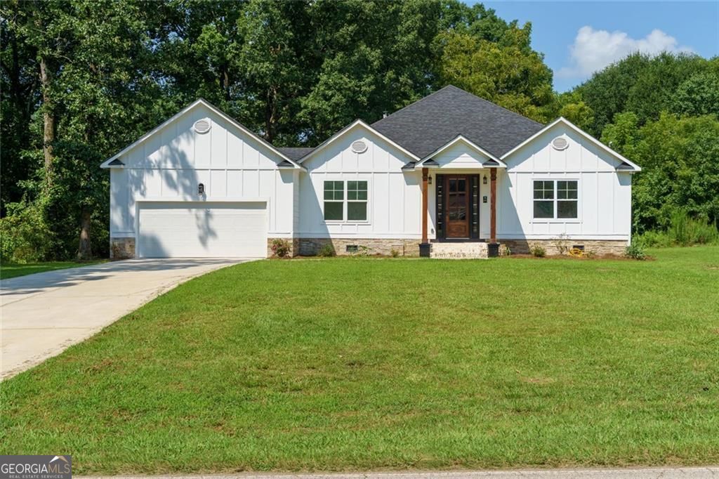 This beautifully updated single-level home offers an open floor plan with modern finishes throughout. The living room features a sleek in-wall fireplace and flows seamlessly into the stylish kitchen with a granite island, butcher block countertops, and updated cabinetry. The primary suite, located at the front of the home, includes a spa-like bathroom with a soaking tub, walk-in shower, and double vanity. Two additional bedrooms and a renovated full bath provide ample space for family or guests. Additional updates include new flooring, decorative trim and paneling, sliding barn doors, and a mudroom with built-in storage. Outside, a large backyard with a brand-new patio is ideal for entertaining, while the new driveway and two-car garage add convenience. Located near downtown Stone Mountain and Stone Mountain Park, with easy access to I-20, shopping, dining, and schools, this move-in ready home combines comfort and style in a desirable setting.
