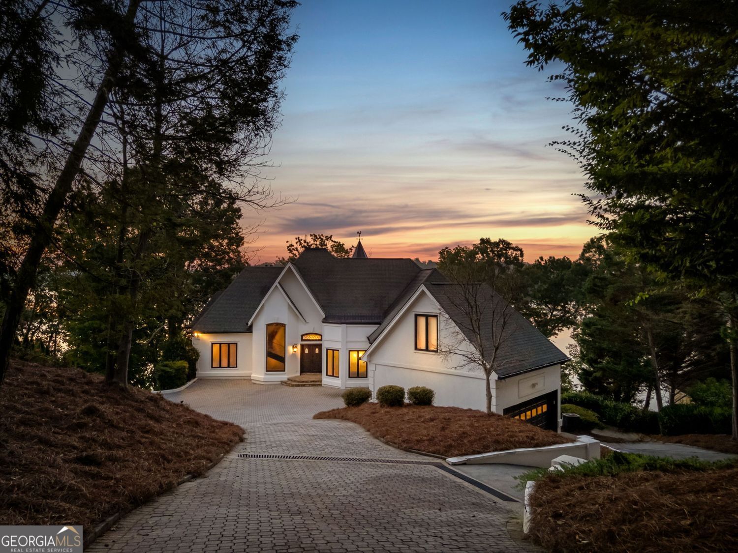 PRICED TO SELL!! Introducing The Chateau on Lanier - lakeside luxury living with this meticulously maintained estate on Lake Lanier. The estate's prime lakefront location includes a private DOUBLE-SLIP dock in DEEP water, which is just an easy stroll from the home. This residence is a truly exceptional, fully furnished 8-bedroom, 6.5-bathroom gated home and is perfectly positioned on 0.72 acres, offering breathtaking panoramic lake views from every level. Enter a world of elegance where stunning lake views are framed by multi-level balconies and expansive windows. The main level of this three-story estate features a chef's kitchen with commercial-grade stainless steel appliances, seamlessly flowing into the keeping room and dining area-all with captivating lake views. The family room opens to a balcony, making a perfect place to enjoy your morning coffee. The main level includes a massive mudroom with double washers and dryers, a sink, and a rear staircase leading to the terrace level. Two spacious guest bedrooms, one a secondary primary suite with their own private en suite bathroom, enhance the main level's appeal. Take the spiral staircase to the upper level, where the primary suite offers French doors, ample space, and panoramic lakefront views. This suite features a massive en suite bathroom with double vanities, a whirlpool tub, a grand tile walk-in shower, and a custom-built closet with an additional washer and dryer for added convenience. An additional secondary bedroom on this level also boasts an updated en suite bathroom. The terrace level is an entertainer's dream or the perfect in-law suite, complete with a full kitchen, bar, and living room. This level also includes three guest bedrooms and two full bathrooms, plus a spacious bunkroom ideal for a media room or recreational space that could be easily converted back to an additional two car garage with tons of storage. Enjoy year-round swimming in the heated pool. Perfectly located just off Dawsonville Highway, this estate is minutes away from dining, shopping, and more, offering the ultimate blend of serene lakefront living and modern convenience. Don't miss the opportunity to own this exceptional lakeside retreat.