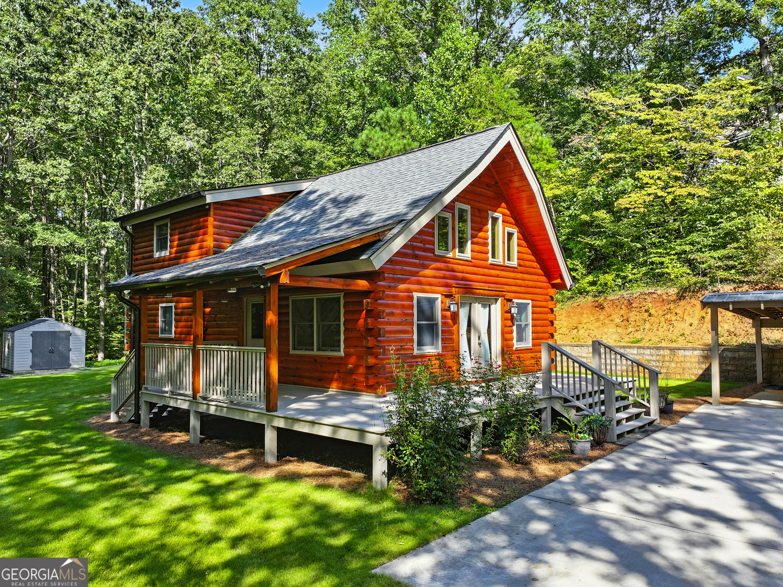 Nestled among the trees, this enchanting log cabin is the perfect blend of rustic charm and modern comfort. With its golden pine walls, soaring ceilings, and natural light streaming through tall windows, every corner feels warm, cozy, and full of character. Step inside to an open living space anchored by a wall of windows and double doors leading out to the wrap-around porch-ideal for sipping coffee while listening to the whispers of the woods. The kitchen offers dark cabinetry for a striking contrast against the glowing wood interior, with a nearby breakfast nook that's perfect for morning sunshine. The main-level primary suite is spacious and private, complete with its own bath and walk-in closet. Upstairs, two additional bedrooms, a full bath, and a bonus room provide plenty of space for family, guests, or a creative retreat-all overlooking the great room below. Outside, a lush yard is framed by wooded privacy, with multiple outbuildings for storage, hobbies, or workshop space. Whether you're looking for a peaceful full-time home or a storybook weekend getaway, this Weaver Road charmer invites you to slow down, breathe deep, and enjoy life in the woods.