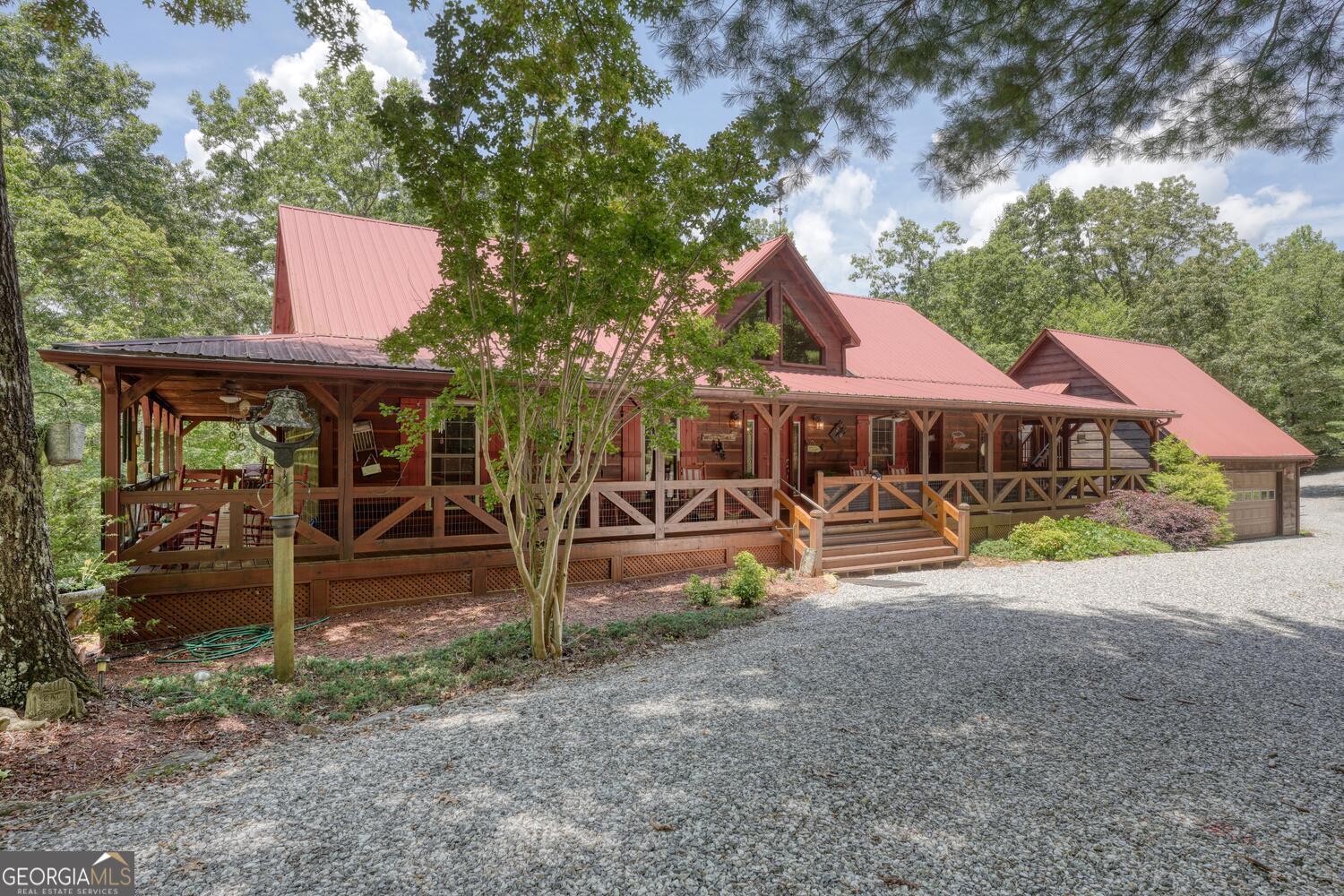 Private Mountain Retreat on 5.31 Unrestricted Acres! Tucked away at the end of a quiet road, this stunning cabin offers the ultimate blend of rustic charm & cabin vibes. With 5.31 unrestricted acres of serene privacy, this beautifully crafted home features hand-milled wood siding & a durable metal roof. A newer Generac generator ensures peace of mind year-round. Step inside to wide wood plank flooring, soaring cathedral ceilings, & a gorgeous rock fireplace w/gas logs creating a warm, inviting ambiance. The kitchen is thoughtfully designed with a pantry, breakfast counter, new gas cooktop, & it opens to a sunny light-filled sunroom perfect for morning coffee or afternoon relaxing. Fiber optic internet is available. The main level includes 1 bedroom & 1.5 baths, including a luxurious master suite with a jetted tub, step-in tiled shower, double vanities, two walk-in closets, & a private laundry area w/utility sink & makeup vanity. Additional interior highlights include a central vacuum system, zoned HVAC w/humidifier, & spacious layout throughout. The finished basement offers incredible space w/a large family room & game room combination, accented by charming pecky cypress walls. You'll also find 1 additional bedroom, a full bathroom, a flex space for more guests & a large storage area in the mechanical room. Step outside to the oversized deck ideal for entertaining, relaxing, or taking in the peaceful views of the mature grapevines & trees. The attached two-car garage features a well-insulated finished craft room, while down the drive, a second detached garage offers a tall bay door, bright LED lighting, half bath, gas water heater, water filtration, & washer/dryer hookups. Above this garage is an open studio apartment w/a full bath & living space perfect for guests, in-laws, or potential rental income. Don't miss this rare opportunity to own a peaceful retreat w/room to breathe, work, & entertain-located just 15 minutes from town but in a world of its own.