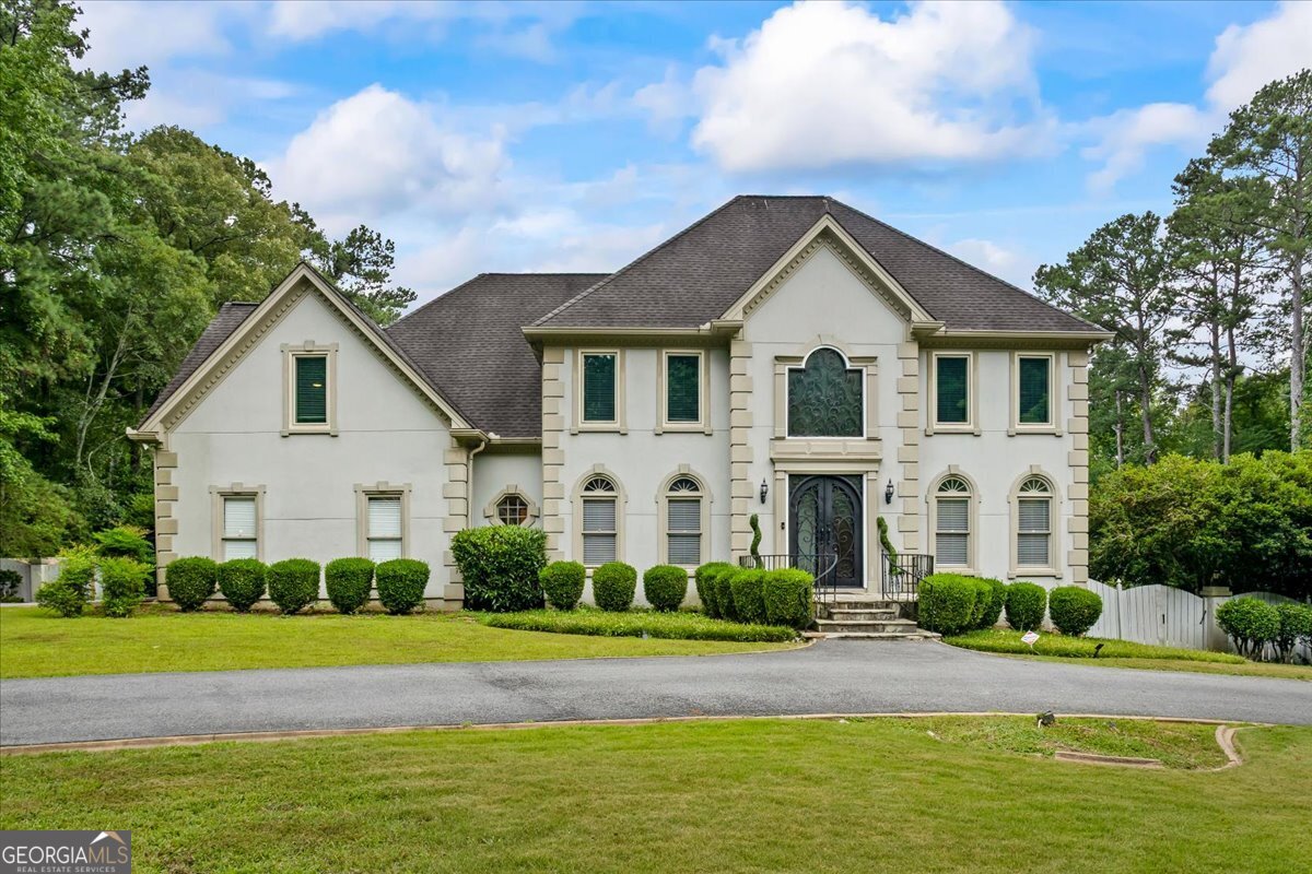 Welcome to this exceptional custom-built residence nestled in the highly sought-after Bridgewater community, perfectly positioned on nearly 2 private acres backing up to serene Lake Matthew. From the moment you enter the grand two-story foyer, you'll be captivated by the refined elegance and thoughtfully designed open layout ideal for luxurious living and entertaining. The main level boasts a seamless flow featuring a richly appointed wood-accented office, a chef's dream kitchen with an expansive island, and a generous eat-in area that opens into an oversized sunroom. Enjoy panoramic views of the resort-style backyard showcasing a spacious deck, an in-ground saltwater pool, a half basketball court, and a charming pool house-your private oasis awaits. Upstairs, you'll find four oversized bedrooms, including two lavish primary suites, three full bathrooms, and a gallery-style hallway overlooking the soaring family room below. The partially finished basement offers additional living space with endless potential for customization. This one-of-a-kind home effortlessly blends comfort, sophistication, and resort-style amenities-all within an exclusive, tranquil setting.