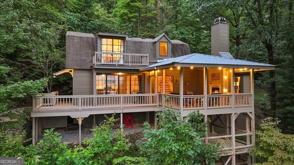 Storybook Mountain Cottage with Long Range Panoramic Views! This enchanting 2-bedroom, 2.5-bath mountain cottage blends vintage European charm with modern comfort, offering a rare combination of privacy, character, and breathtaking long-range views. Set on over 5 acres-with an additional 2.5-acre lot available-the home feels worlds away yet sits just 9 miles from downtown Ellijay, 80 miles from Atlanta, and 60 miles from Chattanooga. Storybook inspired construction with gambrel roof, painted wood walls, and hardwood floors create a timeless appeal, while large custom steel windows and European French casement windows flood the interiors with natural light and frame sweeping long-range mountain vistas. Awe-inspiring views from every room with vaulted ceilings in the bedrooms, custom cabinetry with marble tops, and walk-in closets in both bedrooms and total of 2 fireplaces. Outdoor living is just as inviting, with over 700 square feet of porches and covered decks to enjoy year-round clear mountain views. Meticulously maintained and cared for by a single owner, with recent updates that include, new exterior paint (2025), a new well (2023), a regularly serviced HVAC system (installed in 2016), a new hot water heater (2019), an upgraded septic system, and a brand-new electrical service and meter base in late 2024. The home also offers a partially finished, conditioned basement for a 3rd bedroom or other future expansion. Located in a gated community with low annual dues, the property is minutes from Historic Downtown Ellijay and Carters Lake and close to hiking, mountain biking, boating, and swimming. The additional 2.5-acre lot is cleared with septic already installed, providing a ready homesite or future investment opportunity. With its rare privacy, panoramic views, and European-inspired character, this mountain retreat is truly one of a kind. Perfect for full time living, weekend getaways or potential top-producing short term rental investment property.