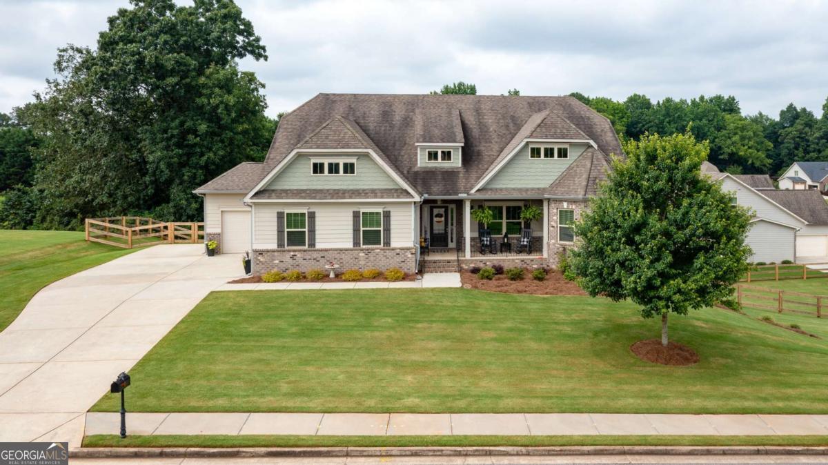 Welcome to Riverstone Plantation - Your Dream Home Awaits! Introducing this stunning like-new, move-in ready Craftsman-style home located on a desirable corner lot in the sought-after Riverstone Plantation (Hillside) community of Gainesville/Forsyth. Built in 2017 and meticulously maintained, this 5-bedroom, 4.5-bath residence with a master on the main and full daylight walk-out basement truly checks all the boxes! Step inside from the welcoming covered front porch to find a bright, open-concept layout with timeless hardwood floors, fresh neutral tones, and abundant natural light. The heart of the home is the gourmet kitchen, featuring sparkling granite countertops, a stylish glass tile backsplash, stainless steel appliances (including a gas cooktop, double oven, dishwasher, and new microwave), and a large granite peninsula with seating for eight-perfect for entertaining. Adjacent to the kitchen, the spacious family room centers around a cozy stone fireplace with windows overlooking the tranquil backyard. A large breakfast area and a beautifully detailed formal dining room with board and batten trim provide plenty of room for casual meals or holiday feasts. Enjoy peaceful mornings or unwind in the evenings on the serene screened-in porch with expansive wooded views. The oversized main-level primary suite boasts a trey ceiling, crown molding, and a luxurious ensuite bath complete with dual vanities, soaking tub, separate tile shower, tile flooring, and dual walk-in closets. Also on the main level are two additional bedrooms connected by a Jack and Jill bath, each with separate vanities. A spacious laundry/mudroom with utility sink adds function and convenience. Upstairs, you'll find another generously sized bedroom with a full bath and easy access to a spray-foam insulated, climate-controlled attic storage area. The fully finished basement offers endless possibilities with a large media room (with walk-in closet), expansive rec room/flex space, additional bedroom, and full bath-plus unfinished areas perfect for storage or future customization. Car enthusiasts or hobbyists will love the three-car garage configuration: a two-car side entry plus a rare third front-entry garage ideal for a golf cart, tools, or lawn equipment. Additional features include: Energy-efficient upgrades: spray foam insulation, tankless water heater, energy-efficient windows, and heat pump Recent updates: new exterior double doors, new backyard stairs, fencing, enhanced landscaping, flood lights, and updated lighting in dining and breakfast rooms. Riverstone Plantation offers resort-style amenities including six tennis courts, a swimming pool, basketball courts, pickle ball courts and a playground. Enjoy an active, social community with planned events year-round. Conveniently located near Hwy 400, East Forsyth High School, shopping, dining, and top destinations like Lake Lanier, Downtown Gainesville, North GA Premium Outlets, Cumming City Center, and Alpharetta. Don't miss your chance to own this exceptional home in one of Forsyth County's most desirable communities. Schedule your private tour today