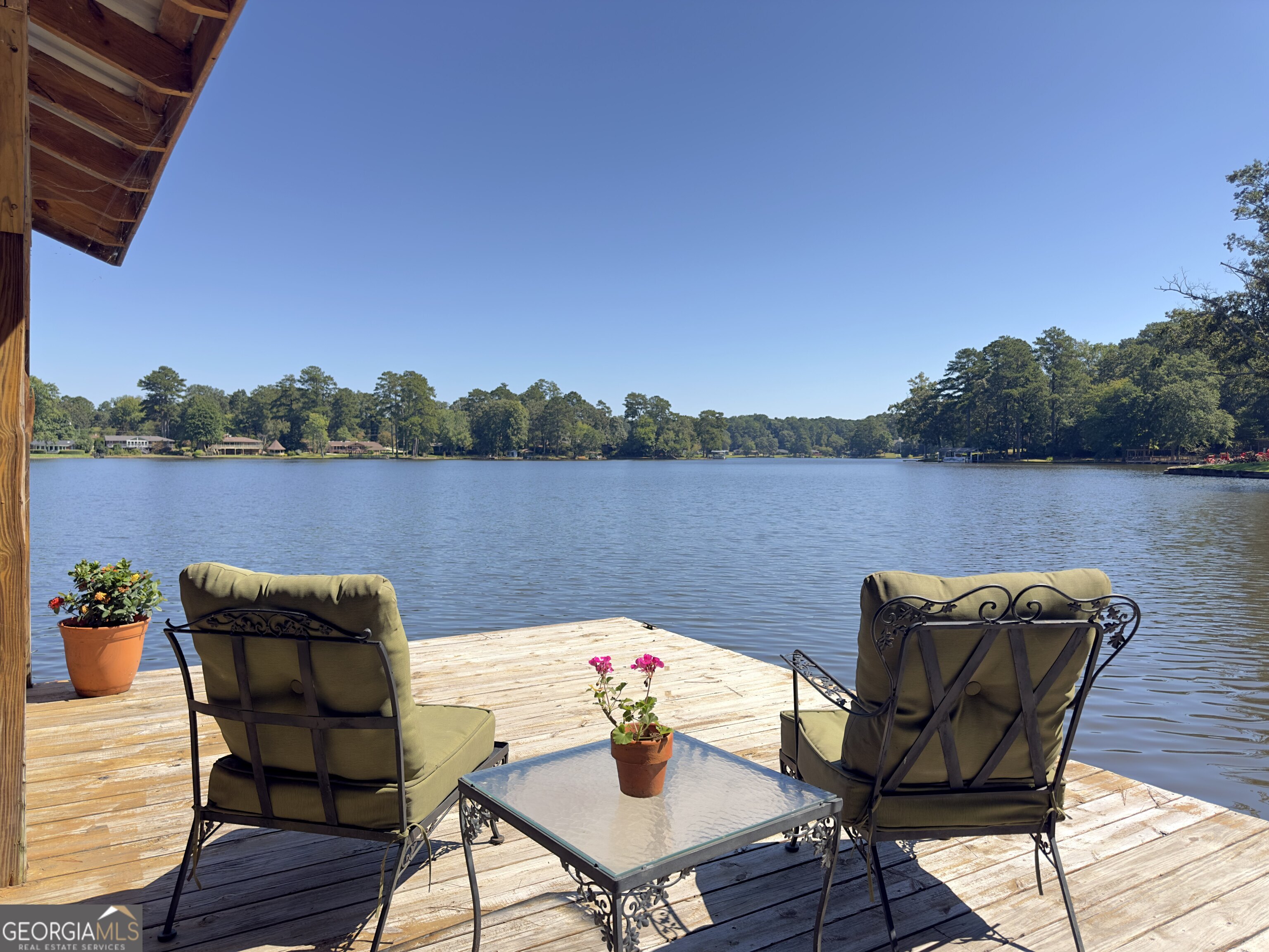 This stunning waterfront home on beautiful Lake Jodeco sits on an expansive private lot with access to deep water and stunning views. As you step into this beautifully updated brick home, you are greeted with a breathtaking panoramic lake view from the entire back of the house. The open floor plan makes it ideal for entertaining, offering plenty of living space. Every room features special touches-from the oversized living room that opens onto the expansive back deck, which runs the full length of the house, to the open kitchen overlooking the lake with ample cabinet space and granite countertops, a tasteful updated laundry room, and the large office/second family room with a private deck and access to the main deck. The master suite features a beautiful custom walk-in closet and ensuite bath, and the main floor boasts gorgeous hardwood floors. Downstairs, you'll find a workout room, game room, built-in bar, additional storage, and a workshop. The backyard is breathtaking, with a well-manicured zoysia lawn, 108 feet of prime fishing water, and lake views. A newly built dock features a covered boat slip and an additional covered and open area for relaxation and entertaining while enjoying the sunsets. To the side of the property, there's a paved path and private boat ramp, along with an additional storage shed perfect for lawn equipment or the highly sought-after She Shed. Lake Jodeco provides 85 acres for you and your family to enjoy boating, swimming, and fishing for trophy bass and crappie. Whether you're enjoying retirement or raising a family, this lake property is perfect for you. Lake Jodeco is a private lake just south of Atlanta, only 13 miles from Atlanta Hartsfield-Jackson and 18 miles from Downtown Atlanta. Additional upgrades include a new roof in 2025, new HVAC in 2024, new carpet installed downstairs in 2025, a new back deck, a 4-year-old dock, a poured cement lake wall, an in-ground irrigation system with a new pump (no extra cost to water the lawn), and a fenced backyard. Welcome home to your private oasis!