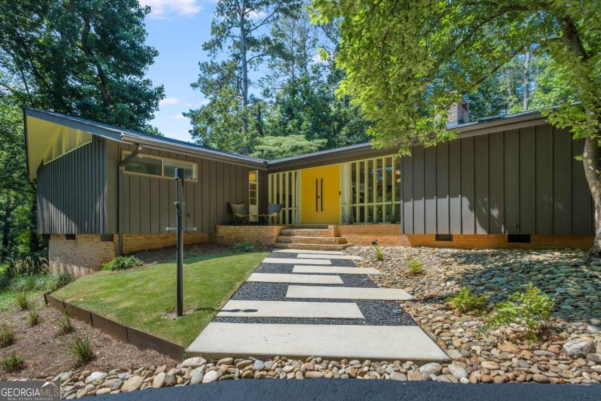 ***Stunning Custom Mid-Century Modern Ranch in Tucker's Smoke Rise Community - Renovated Luxury with Finished Terrace Level & Designer Details*** Welcome to this rare architectural gem-a custom-built mid-century modern ranch set on nearly an acre in the City of Tucker, just minutes from Kanawha Golf & Country Club. With timeless design, custom upgrades, and a fully renovated, this home offers the perfect blend of modern, comfort, and natural beauty. The uniquely designed mail box, long winding driveway, and customs walkway set the tone for this Mid-Century Beauty. Enter through double front doors flanked by floor-to-ceiling windows into a spacious foyer with natural stone flooring. From there, the home opens into a dramatic great room featuring cathedral ceilings, open stairway with custom railing to the terraced level, a custom copper-hooded double-sided fireplace with slate stone accents, and a wall of floor-to-ceiling glass that brings the outdoors in. The chef's kitchen is a showpiece-highlighted by a 9-foot quartz island, vaulted ceiling and skylights, professional-grade 5-burner gas stove with convection oven, an additional oven and microwave, and other newer stainless steel appliances. A dedicated prep/bar area includes open shelving, pantry space, and a copper sink, perfect for entertaining or making that morning cup of coffee! Adjacent to the kitchen and dining room is a sun room with floor-to-ceiling windows and a three door slider, offering panoramic views of the backyard and natural light throughout the main living areas. Just off the oversized carport and kitchen, a smartly designed mudroom/laundry room with built-in storage adds daily functionality with style. A half bath is located just of the kitchen. The primary suite is a tranquil retreat featuring a custom walnut-accented bed wall, large windows, a walk-in closet with built-in organizers and aluminum wall panels, and private access to a large composite deck-perfect for unwinding. The spa-like en suite bath features a floating double vanity, oversized frame-less shower with multi function rain head, a freestanding soaking tub beneath a large skylight with a wireless shade. Sleek finishes including quartz, high end porcelain, and Delta/Hansgrohe chrome fixtures. Two additional bedrooms upstairs feature cathedral ceilings, custom closets, and classic mid-century style windows. The renovated hall bath includes a floating double vanity, Toto toilet, modern porcelain tile, and a charming original mid-century window accent. The fully renovated terrace-level offers incredible versatility-complete with a large media room, new second kitchen, large bedroom, full bathroom, gym or optional 5th bedroom, large work shop and lots of additional storage space. Perfect for an in-law suite, guest quarters, teen suit, or income-producing rental-this space is bright, open, and highly functional. The lower level also has a separate parking area, outdoor path, patio and private entrance. Outdoors, the nearly 1-acre lot is both private and professionally landscaped, with a mix of wooded areas for seclusion and a lush Zoysia sodded lawn. Enjoy stone pathways and steps, river rock beds, and a freshly sealed driveway that adds to the home's curb appeal and ease of access. Recent updates include HVAC, Water Heater, Windows, Roof/Gutters/Skylights, most of the plumbing including the main water line, and so much more! More than just a neighborhood, Smoke Rise is a lifestyle. Known for it's rolling hills, mature trees, large private lots and custom homes. Located just minutes from Smoke Rise Country Club, which offers golf, tennis, dining, and social events, and within the charming City of Tucker, known for its vibrant Main Street, community events, and excellent schools. Easy access to major highways and outdoor recreation at nearby city parks. This is a rare opportunity to enjoy space, privacy, and convenience in one of Tucker's premier neighborhoods. Don't delay!