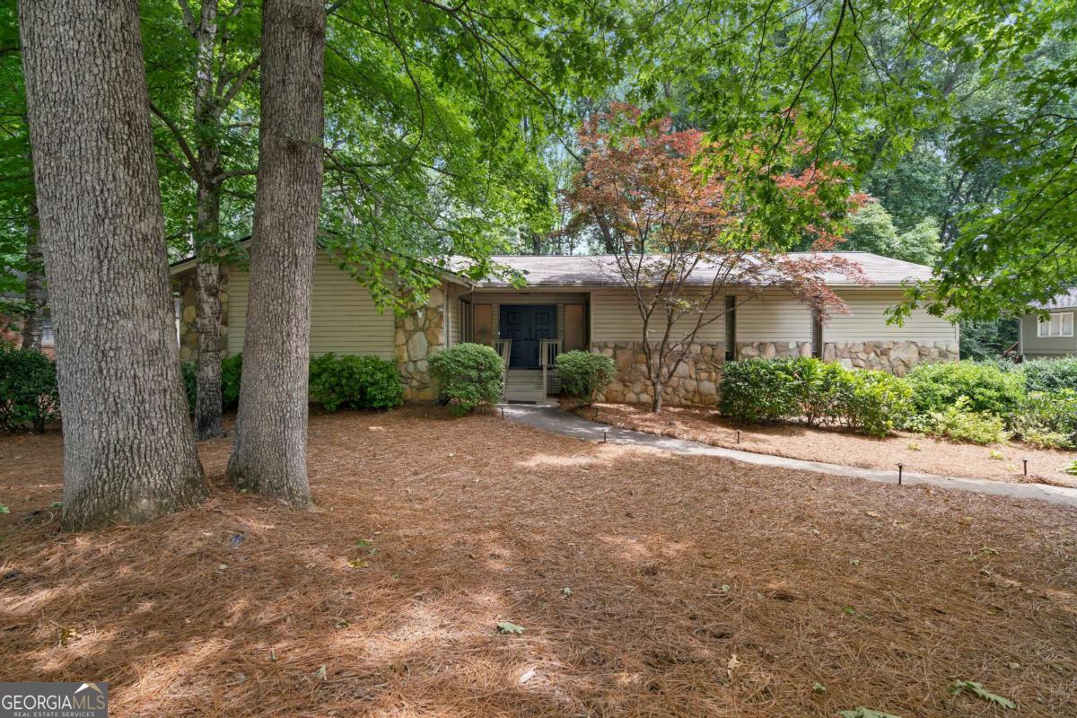 This beautiful raised ranch offers timeless charm and spacious living across two levels. Enter through a dramatic double door foyer with frosted glass windows and stone flooring. The impressive great room features vaulted natural wood beam ceilings, a wall of built-ins, floor to ceiling windows, and a striking stone fireplace, perfect for entertaining or relaxing. Enjoy outdoor living on the spacious deck with built-in bench seating, just off the great room. The kitchen is both stylish and functional with granite countertops, abundant cabinetry, stainless steel cooktop, wall oven, and a bay window breakfast nook. A separate dining room offers space for gatherings of 8+ with generous natural light. The main level includes three bedrooms, including a primary suite with marble top vanity and soaking tub/shower, a full hall bath with double vanities and tile shower, and a convenient half bath. Downstairs, the finished lower level is a true owner's retreat, complete with a large bedroom featuring tray ceilings, a cozy sitting area with a stone accent wall and fireplace, an expansive ensuite with double vanities, a marble soaking tub, walk-in shower, and huge custom closet. Lower level also features a laundry room, extra storage/workshop, and access to a private covered deck. Finished off with a 2 car drive under garage and a new HVAC system, this home is a rare blend of character, comfort, and space!
