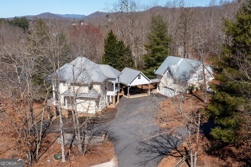 MOTIVATED SELLER ON LAKE CHATUGE!! Embrace the essence of lakeside living with this exceptional North Carolina mountain retreat, perfectly positioned along the serene shores of Lake Chatuge. This captivating 3-bedroom home is designed to maximize your enjoyment of the natural beauty that surrounds it. The open floor plan & great room with its cathedral ceiling and inviting gas log fireplace set the stage for comfortable living & entertaining. Stainless steel appliances in the kitchen pair with functionality & style, while the spacious back deck offers a tranquil vantage point to admire the lake. Accommodations include an indulgent master bedroom complete with a sitting area, and a secondary master suite on the upper level, each offering private havens within the home. The lower level extends your living space with an additional bedroom and bathroom, along with its own living room and second kitchen, perfect for guests or as an in-law suite. Outside, the property excels with a lakeside pavilion including a kitchen for outdoor gatherings, and a covered single slip boat dock for leisurely days on the water. Parking and storage are ample with a 2-car carport and a HUGE 3-bay garage featuring a 1 bedroom/1 bathroom apartment above, offering extra space for visitors. Located within minutes from the charming downtown areas of Hayesville, NC, and Hiawassee, GA, this home delivers both seclusion and convenience for the ultimate retreat. This enchanting property is more than just a home-it's an experience that promises a lifestyle of peaceful luxury and lakeside adventure.