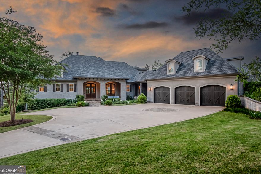 Step into a world of unparalleled luxury and elegance with this lakefront masterpiece crafted by DreamBuilt in Horseshoe Bend, Reynolds Lake Oconee. Offering spectacular views of the lake, sunset and the Jack Nicklaus golf course, this home, featured on "Mansion Global" TV show, offers clean lines and a lifestyle of comfort and refinement. Step through the grand entrance, and be greeted by an expansive great room adorned with custom-designed built-in cabinets and a fireplace, Adjacent, a reading room/library awaits, perfect for moments of quiet contemplation.The primary suite epitomizes luxury with its layout, complete with custom built-in cabinets, and a primary bath boasting dual vanities, Kohler lighted mirrors, towel warmers. Convenience is paramount, with a washer and dryer tucked away for added ease.For the culinary enthusiast,this home boasts three kitchens, each designed for efficiency and equipped with state-of-the-art commercial-grade appliances. The main kitchen is a masterpiece of design, featuring sleek minimalist cabinets, Caesarstone countertops and backsplashes, and dual dishwashers. A large pantry with another full refrigerator, ensures ample storage space to hide small appliances, while a mudroom with custom lockers and storage, provides a seamless transition to the outdoors and connects to the three-car garage, complete with a 220-EV charger and full house Generac generator. Ascend the glass and steel staircase to discover a loft studio with a full bathroom and bar area, offering a retreat and versatility, perfect for studio or bunk room. The expansive covered porch beckons with a second kitchen and fireplace, featuring commercial grade appliances including a salamander broiler. Adjacent to it is the stunning all-season dining area, with retractable vinyl and screens offering spectacular lake views allowing you to bring the outside in. Descend to the terrace level featuring a large family and TV room with a wet bar, custom buffet counters, temperature-controlled wine room, gym,and three en-suite bedrooms with lake views. Step outside to the expansive screened porch, where dining and lounge areas await. The outdoor amenities include a 40-ft walk-out infinity pool and spa, a sunken fire pit for gatherings, a third kitchen with grill and bar area, private boat dock, and a "Cool Deck" path leading to the water's edge. Boat to the golf course or to dinner with friends from your dock. Membership available.