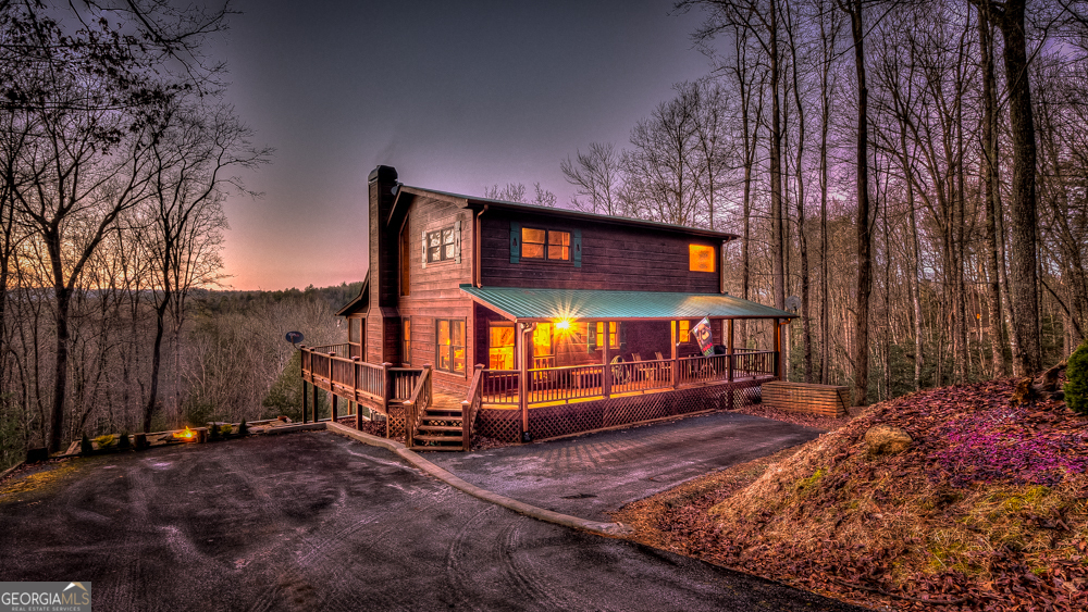 Nestled high on a serene hillside in the coveted Aska Adventure Area, Resting Bear Retreat is a fully furnished, turnkey mountain escape with breathtaking long-range views from every angle. This 3-bedroom + loft + bunk area cabin combines laid-back comfort with professional decor, offering the perfect balance of rustic charm and modern luxury. Step inside and be welcomed by soaring vaulted ceilings, warm hardwood floors, oversized windows that flood the space with natural light, and custom log stair rails leading to a cozy sleeping loft. The great room features a striking stone fireplace and french doors that open to expansive wraparound decks, designed to maximize the view and fresh mountain air. The terrace level is made for entertaining, with a full game room including a pool table and a second gas fireplace. Step outside to enjoy the lower deck's porch swing or relax in the hot tub while soaking in the peaceful surroundings. The upper deck features a screened-in porch with ample seating, a charcoal grill, and the backyard boasts a fire pit for evenings under the stars. Set on 1.7 private acres with a long driveway and generous guest parking, this cabin offers plenty of room to gather, unwind, and explore. With 3 bedrooms, an open loft sleeping area, and additional bunks on the terrace level, there's space for everyone. A proven short-term rental success, Resting Bear Retreat is being sold fully furnished - a true turnkey investment or a ready-to-enjoy personal getaway in the Blue Ridge mountains.