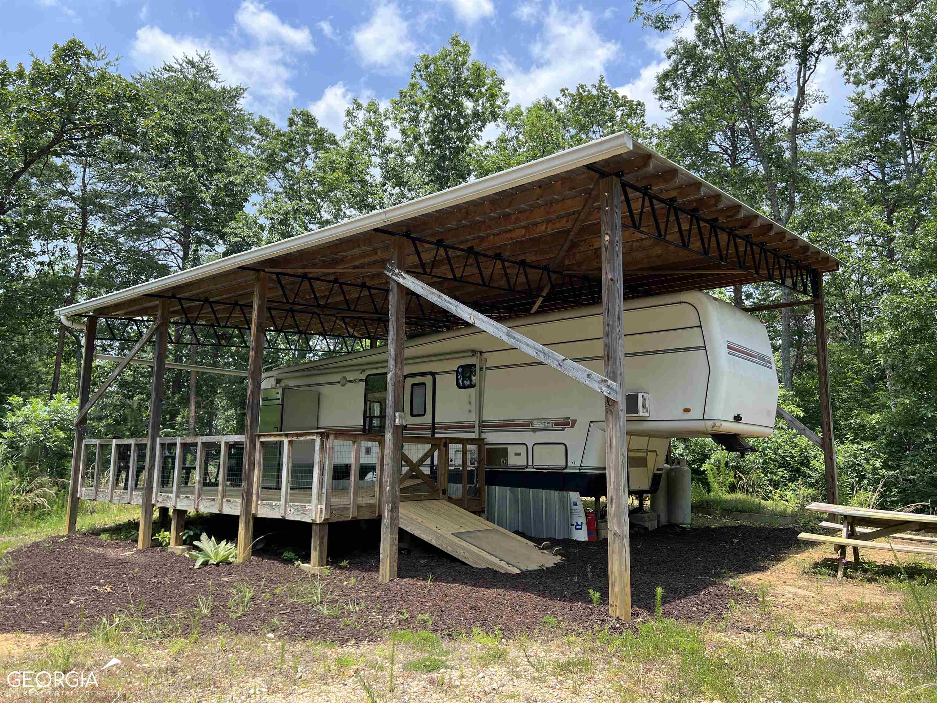 NO SHOWINGS ON SATURDAY - NO EXCEPTIONS! FROM SELLER - “Discover your dream hideaway in the heart of nature! This amazing property just minutes from Carters Lake offers a secluded and off-grid glamping experience amidst 20 +/- acres of untouched forest. There are two beautiful building sites. Nestled within the tranquil surroundings, you'll find everything you need for a comfortable stay. To enhance your clamping experience, included with the sale of the property is a recently renovated RV, a 2100-gallon water storage tank collects rainwater from the pole barn's roof, providing a water supply. The solar panels on the roof provide power and the propane generator does the job when the AC needs to be turned up mid-summer. There is a propane heater to keep you warm and a cozy renovated newly bedroom and bathroom as well as new gas stove and subway tile backsplash. Picture yourself relaxing on the spacious 12'x24' front porch, where you can watch the local wildlife like deer, turkeys, and maybe even the occasional black bear! Additionally, the property is adjacent to a seasonal stream, offering soothing sounds and a stunning forest backdrop. For outdoor enthusiasts, this location is a paradise. You'll be close to the renowned Carters Lake and an array of hiking trails, providing endless opportunities for adventure and exploration. Stay connected with the world as cellular wifi from AT&T is available, allowing you to share your wonderful experiences with friends and family, stream movies, take zoom calls or whatever your bandwidth needs may be. The property is also conveniently located - within a 30-45 minute drive to nearby vibrant towns such as Cartersville, Jasper, Ellijay, Calhoun, Dalton, and Chatsworth. You'll have access to a variety of amenities and services while enjoying the serenity of your secluded retreat. Just 1 mile off 411 for easy access yet complete seclusion. Don't miss out on this incredible opportunity to own your very own slice of nature's paradise. Embrace the beauty, tranquility, and adventure that await you in this remarkable off-grid glamping haven. We have enjoyed it and are ready to let someone else experience the secluded sounds that only nature can provide.” NO SHOWINGS ON SATURDAY - NO EXCEPTIONS! - MORE PICTURES AND DRONE VIDEO COMING SOON! - SECLUDED PRIVACY WITH POWER ON THE PROPERTY! - POLE BARN ON PROPERTY WITH RV UNDER IT AND SHIPPING CONTAINER NEXT TO THE POLE BARN - SELLER DESIGNED THIS TO BE OFF THE GRID LIVING. - POWER SOURCE WAS DAMAGED BUT SHIPPING CONTAINER THAT WAS STORING IT CAN STILL BE USED FOR THE NEXT OWNER FOR STORAGE PUTTING IN BATTERY BACKUP AND SOLAR PANELS OR JUST CONNECT TO THE POWER AT THE STREET. - PROPERTY IS LOCATED ON A DIRT THAT IS NOT MAINTAINED BY GORDON COUNTY - TRUCK OR SUV RECOMMEND FOR ACCESSING PROPERTY. THIS PROPERTY FEATURES: MATURES HARDWOODS AND PINES. - TOPOGRAPHY: STEEP TO ROLLING. - UTILITIES: POWER AT THE PRIVATE DIRT ROAD (GEORGIA POWER) - SOLD AS IS! SELLER IS SELLING THE REAL ESTATE - DEPENDING UPON THE PRICE WILL GIVE THE BUYER THE RV ON THE PROPERTY. - SHIPPING CONTAINER ON THE PROPERTY IS INCLUDED IN THE SALE. - PRIVATE DIRT ROAD FRONTAGE. - RV HAS OPEN LIVING/DINING/KITCHEN & BATHROOM & PRIVATE BEDROOM. - RAIN CATCHMENT SYSTEM FOR COLLECTING RAIN WATER OFF OF THE ROOF OF THE POLE BARN. - YOU NEED TO PUT IN 34.580790, -84.693784 INTO GOOGLE MAPS OR APPLE MAPS TO GET DIRECTIONS. ADDRESS OF PROPERTY WILL NOT CORRECTLY MAP ON SOME MAPPING SYSTEMS. - UNTIL GATE IS REPAIRED - YOU HAVE TO REMOVE THE PIN FROM THE GATE TO OPEN THE GATE. (PLEASE DO NOT DAMAGE FURTHER.) - OTHER GREAT HOMESITES ON THE PROPERTY