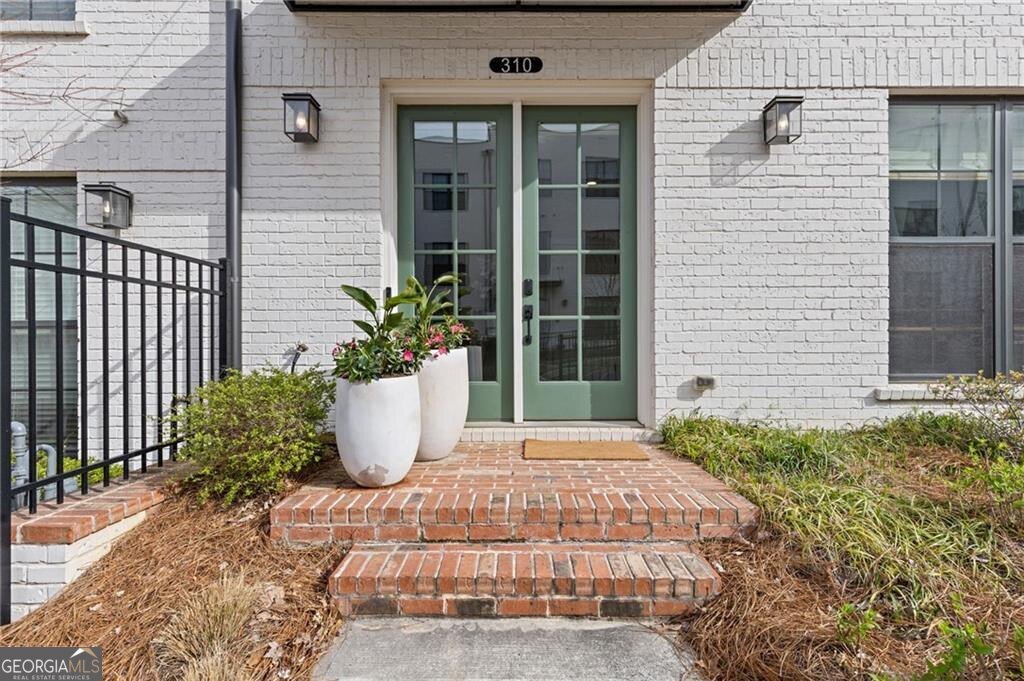 Spacious, Stylish, and Steps from Downtown Alpharetta - This beautifully upgraded three-story townhome truly lives like a single-family home. From the generous open-concept layout to the designer finishes throughout, every detail offers comfort, functionality, and timeless style-right in the heart of Alpharetta. At the center of the home is a spacious main floor where the open layout seamlessly connects the kitchen, dining area, and family room-ideal for both everyday living and entertaining. The gourmet kitchen is loaded with upgrades, including high-end quartz countertops, an oversized island with seating for 4-5, a coffee bar, upgraded cabinet hardware, and designer pendant lighting. Hardwood flooring and custom window treatments flow throughout, while a painted brick fireplace wall adds charm and warmth. Additional hardwired sconces in the living room and powder room elevate the lighting design, and the dining area pops with designer wallpaper. Step outside to a large covered deck-perfect for enjoying your morning coffee or entertaining guests. Upstairs, the owner's suite offers a peaceful retreat with custom paint, upgraded lighting, and elegant molding in the bath. The generously sized primary bathroom features a spacious, fully tiled walk-in shower, two separate vanities, and custom LED mirrors framed with rich wood trim-giving the space a high-end, spa-like feel. The suite also includes an expansive custom walk-in closet, offering both function and style with thoughtful organization and ample storage. Two additional bedrooms, a full hallway bath with upgraded tile, lighting, and mirror, and a conveniently located laundry room complete this level. Custom plantation shutters and upgraded hardwood floors carry throughout for a consistent, upscale look. The entry level features a flexible fourth bedroom with custom closet shelving and upgraded lighting-ideal for a guest suite or home office. Additional highlights include upgraded hardwood flooring, custom window treatments, and statement molding along the staircase wall. The large two-car garage (with 2 separate doors to easily fit 2 cars) includes custom built-in storage, offering extra space for organization and convenience. The Maxwell community includes resort-style amenities such as a pool, clubhouse, two firepit areas, and a bocce ball court. Just a short walk away is The Maxwell Retail district, offering great restaurants and shopping. You'll also enjoy direct access to the Alpha Loop-a 12-foot-wide urban trail network connecting Downtown Alpharetta, Avalon, the North Point Eco District, and Northwinds. Conveniently located just one mile from GA-400, this townhome offers easy access for commuting while placing you steps from the best of Alpharetta living.