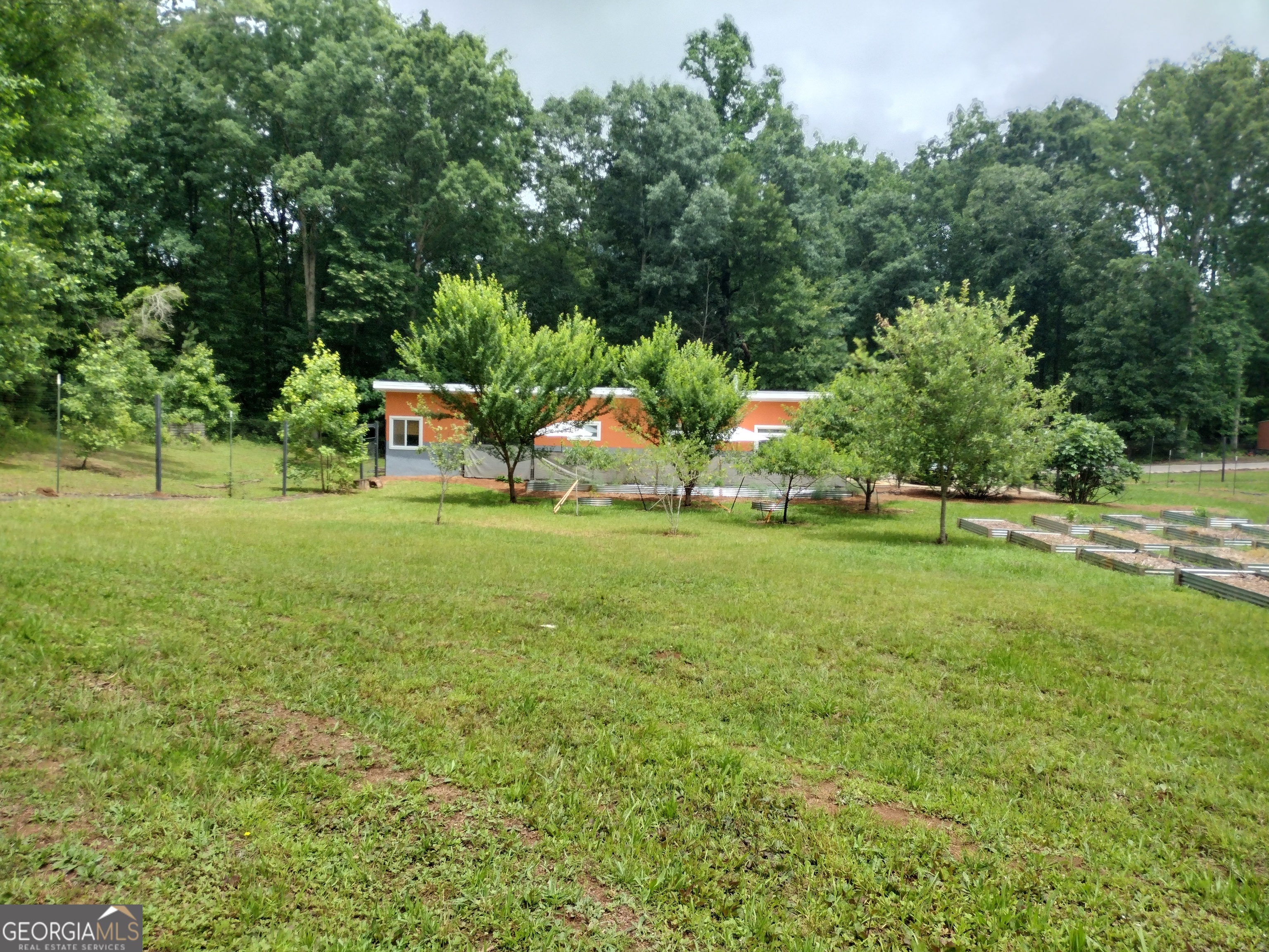 Looking for a peaceful retreat with plenty of space to spread out, enjoy nature, and still be close to town? This unique custom built 2-bedroom, 1-bath home blends thoughtful design with energy-efficient living - plus it's full of character and cozy charm. With 1,092 square feet of heated interior space and an extra 200 square feet of breezeway that doubles as a private hangout, you'll feel right at home. Need more room? There's also a 288 square foot additional dwelling unit already wired and ready for your personal touch. Inside, the two spacious bedrooms include a mini apartment setup complete with a kitchenette. Outside, relax or entertain on a 400 square foot front deck, roast s'mores by the custom fire pit, or host movie nights under the stars with your own outdoor screen. Love fresh produce? You'll adore the professionally fenced garden area, formerly used for organic farming, and enjoy fruit trees like peaches, plums, figs, apples, and pears. Almost 7 acres of land give you wooded views and visits from wildlife. It's like having a nature preserve in your own backyard. Additionally, you will be less than a mile to the new Sandy Creek Park entrance To be completed this year! Modern touches include 12 ft ceilings, a sleek wood stove, energy-friendly appliances, brand-new fiber optic internet, and underground utilities. And yes, everything seen here comes included (except the Ukuleles lol) - just unpack and enjoy. You're tucked away in nature, but only a short drive from downtown, the university, and local favorites like Sandy Creek Park and nearby markets. Come see what relaxed living really looks like.