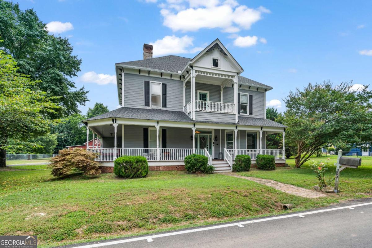 Discover this magnificent historic Victorian-style home at 309 S Main Street in Adairsville. Grandeur and timeless elegance define this stately residence, offering five expansive bedrooms and two and a half bathrooms across 3872 square feet. Situated on a generous 1.14-acre property, there's ample room for gracious Southern living. Step inside and be captivated by the unique ambiance. The grand foyer sets the tone for the refined spaces. Original architectural integrity, with soaring tall ceilings uncommon in newer constructions, blends seamlessly with thoughtful updates. The primary bedroom, conveniently located on the main floor, offers a private sanctuary with a large private bathroom. This suite presents a serene escape, featuring a charming clawfoot tub, ready for your personal touches. Downstairs, a spacious living room is perfectly suited for elegant gatherings or quiet contemplation. This versatile room is enhanced by one of the home's seven decorative fireplaces, contributing to its period charm. Adjacent, the dining room is a true masterpiece. Abundant, towering windows bathe this room in beautiful natural light, creating a dazzling setting. It proudly showcases a beautiful vintage fireplace and mantle, an artistic focal point speaking to the home's heritage of luxury and meticulous craftsmanship. The kitchen, updated with new appliances in 2022, is prepared for your culinary endeavors. A handy pantry provides extra storage, and the laundry room adds to everyday convenience. A half bath serves residents and guests on this floor. Ascending the grand staircase, the upper level features four additional distinctive bedrooms, offering comfortable spaces reflecting the era's architectural grandeur. A full bathroom serves these upper-level bedrooms. Throughout the home, the commanding presence of tall ceilings and exquisite craftsmanship in the substantial trim and crown molding truly define its character. These elements invite abundant natural light, enhancing the overall feeling of spaciousness and warmth from a bygone era of unparalleled style. All seven fireplaces are decorative and not operational. This home has been thoughtfully updated. A new water heater was installed in 2023, and the roof was replaced in 2022. The kitchen received new appliances in 2022, adding practical comforts. The exterior is equally captivating, featuring a quintessential wrap-around porch perfect for relaxing on mild Georgia evenings. This expansive porch offers ample space for seating. An upper porch provides a private spot for morning coffee or winding down the day. Beyond the main house, the sprawling 1.14 acres offer wonderful opportunities for outdoor pursuits. A substantial barn provides additional space for storage, workshops, or creative endeavors, adding immense value and versatility. The Adairsville location offers a lovely community feel, known for its historic charm and welcoming atmosphere, providing desirable privacy and expansive space. It balances tranquil living with convenient access to local amenities within a community that values its heritage. This property is a truly remarkable chance to own a spacious, historic Victorian-style home, built with an eye for luxury and distinctive style. Now benefiting from significant recent updates and generous land, its inviting layout, substantial outdoor features, and inherent grandeur make it ideal for comfortable living and welcoming guests, promising a lifestyle of unique charm and expansive possibilities. To schedule a private viewing and experience all that this Adairsville property has to offer, please connect with us.