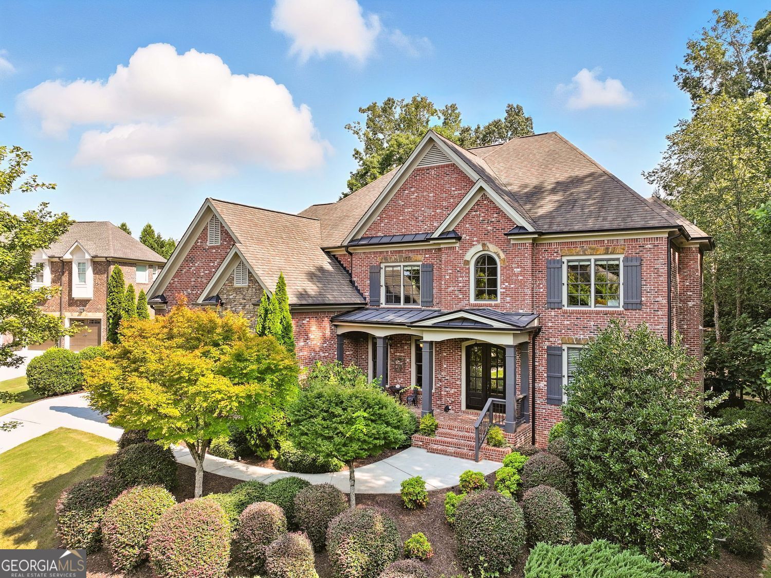 Welcome to your private retreat! This home boasts a beautifully landscaped backyard with mature trees, perfect for peaceful afternoons in a hammock or lively gatherings on the patio. The lush greenery continues around the property, with even more natural beauty visible from the front porch. A spacious three-car side-entry garage features 8-foot-tall doors for added convenience. Step inside through impressive double front doors into a grand two-story foyer. A private office with French doors is conveniently located on the main floor, along with a formal oversized dining room ideal for holiday dinners. The first floor showcases 10-foot ceilings, elegant crown molding, detailed trim work, and custom built-ins framing a striking stone fireplace. The gourmet kitchen overlooks the great room and is a chef's dream, featuring a furniture-style vent hood, hidden walk-in pantry disguised as cabinetry, under-cabinet lighting, double ovens, a gas cooktop, and an oversized island with seating. The sunny breakfast area, surrounded by tall windows, offers stunning views of the wooded backyard. Guests will love the private main-level bedroom with full bath. Upstairs, a large bonus room provides endless possibilities-whether as a media room, exercise space, or playroom. The laundry room is conveniently located on this level. Two bedrooms share a Jack-and-Jill bath, another has a private ensuite, and the luxurious owner's suite impresses with a triple tray ceiling, large ensuite bathroom with dual vanities, soaking tub, separate shower, and an expansive walk-in closet measuring 11' x 17'. The finished basement offers over 1,700 sq. ft. of flexible living space, including a bedroom with full bath, plus additional unfinished areas ideal for storage, hobbies, or lawn equipment with outside access. Located in a prestigious neighborhood within the West Forsyth High School District, residents enjoy fantastic amenities including a clubhouse, pool, and tennis courts. The home is also just minutes from GA-400, Vickery Village, Fowler Park, Midway Park, Big Creek Greenway, shopping, dining, schools, and the library. Don't miss the opportunity to make this stately home your own!