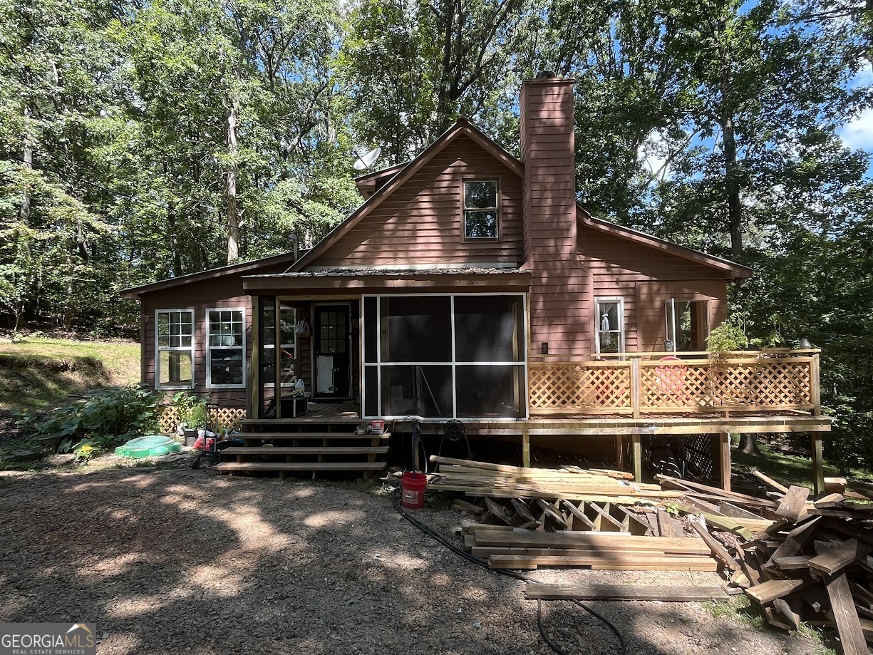 Escape to your own private retreat in the woods! This charming home offers the perfect blend of tranquility and modern comfort, with updated flooring throughout and a stunning stone fireplace that anchors the cozy living space. Enjoy the beauty of every season in the spacious four seasons room, where floor-to-ceiling windows invite natural light and offer serene views of the surrounding forest. Tucked away for seclusion yet conveniently located near Lake Lanier and Don Carter State Park, this property is ideal for nature lovers, outdoor enthusiasts, or anyone seeking peaceful living with easy access to recreation. Don't miss this rare opportunity!