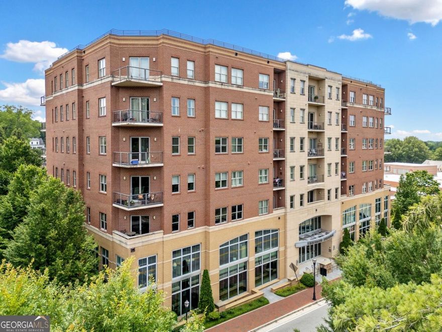 Welcome to Emerson Overlook-just steps from vibrant Marietta Square! This spacious 2-bedroom, 2-bath condo with a bonus den offers the low-maintenance lifestyle you've been looking for in one of Marietta's most sought-after communities.  Watch the exciting parades right from your balcony!   Enjoy a bright, open floor plan in this large corner unit, perfect for entertaining or relaxing at home. The modern kitchen features stainless steel appliances, sleek countertops, and plenty of cabinetry. The living and dining areas flow effortlessly, and large windows offer expansive views that make this home truly special.  You'll love the bonus den-ideal for an office or guest space-and the generous bedrooms with ample closet space. This unit includes a private storage area in the basement and two covered garage parking spaces located in a prime spot close to the entrance-a rare and convenient perk!  Residents enjoy access to an on-site fitness center and the unbeatable location-walkable to shops, dining, parks, and all the charm of Marietta Square. Easy access to major highways makes commuting a breeze.  Be sure to look at convenience of parking spots: # 103 and 104.   Large storage shed in basement is #12!