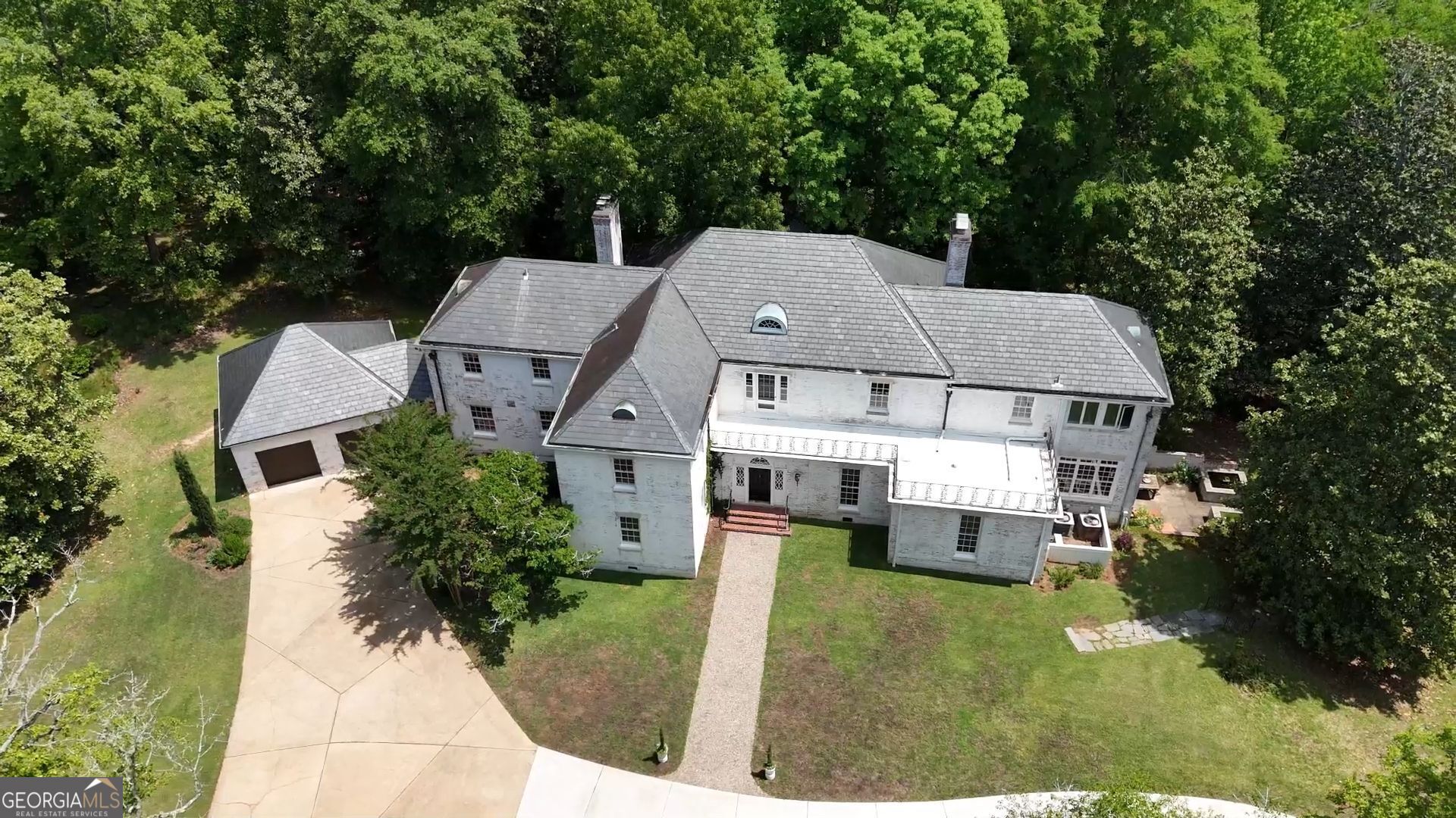 A unique opportunity to acquire the legendary Shirley Hills estate "Greenleaf." Exceptional 1941 Georgian-revival home designed by renowned classicist Elliott Dunwody carefully sited on 13.26 acres of rolling wooded land in the heart of historic Shirley Hills. This elegant home offers 5 bedrooms 6.5 baths and extraordinarily fine original details. The primary facade fronts Twin Pines Drive and exhibits symmetrical massing and monumental Georgia-revival details. The secondary facade exhibits a more playful yet refined asymmetry. A gracious hall connects both entrances and is centered on an elliptical winding staircase of singular elegance and proportions. Formal spaces include a front-to-back parlor with fireplace, a paneled dining room, and lovely library with fireplace. An enchanting sunroom overlooks the serene grounds. A renovated eat-in-kitchen overlooks a keeping room with fireplace and features a commercial gas range, oven, icemaker and subzero refrigeration. A handy mudroom connects an attached 2-car garage. There is a convenient guest suite on the main floor and a charming gallery with patterned floors leads to an additional full guest bath. The second floor includes a sprawling primary suite with dual walk-in closets and dressing areas, bath with shower, and a sunroom/sleeping porch with dreamy, soaking tub. A private guest suite and two large secondary bedrooms with individual yet complementary adjoining baths, laundry room, service stair, and full walk up attic complete the second floor. The walkout, daylit basement bonus room with fireplace leads to an absolutely charming walled terrace with dual fishponds and views of the serene, wooded grounds. This estate has been featured on home tours including the Georgia Trust for Historic Preservation's 2021 Ramble and the treatise on Elliott Dunwody, AIA. An extraordinary opportunity to occupy a grand architectural treasure in an incomparably private wooded setting minutes from vibrant downtown Macon, Interstates 16 and 75, and two major hospitals.