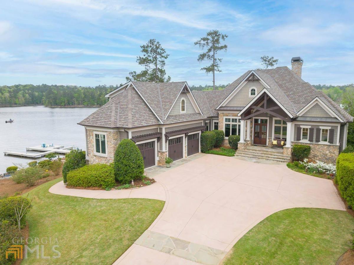 Welcome to your dream lake home! This stunning custom-built property in Reynolds Lake Oconee is situated on a unique and special point lot, boasting over 300 feet of water frontage providing unparalleled views from nearly every angle. As soon as you enter the private driveway, you'll be enveloped in the peaceful surroundings and privacy that this home provides.The backyard is flat featuring a pool overlooking the breathtaking views of the lake surrounded by a spacious deck for lounging and entertaining guests, with several sitting areas throughout the property where you can relax. Inside, you'll find breathtaking views from every room.The home boasts over 6,000 square feet of luxurious living spaces, with fine details and craftsmanship that are sure to impress, featuring four bedrooms, five & a half baths and a stunning office in the terrace level with bath that can be converted into a bedroom.The stunning living room and gorgeous screened porch welcome you with captivating water views. The master suite is an oasis of tranquility offering the perfect retreat from the hustle and bustle of daily life. The kitchen is equipped with state-of-the-art appliances that make cooking a breeze, including top-of-the-line appliances, whether you're a gourmet chef or simply love to entertain.There is a second office with lake views adjacent to the laundry room.The four-season sunroom provides captivating views perfect for watching sunrise every morning. An elevator provides convenient access to the terrace level featuring a beautiful family room, custom well-equipped full bar, beautiful office with bath that can be converted into another bedroom, two en-suite guest bedrooms, steam shower. One of the standout features of the property is the pool, situated in a prime location overlooking the lake with ample space for entertaining. For those who love to spend time on the water, the property offers an expansive flat point backyard with lush greenery, an impressive stretch of waterfront and a private boat dock. The three-car garage offers ample space for vehicles and storage. There is a spacious suite above the garage with full bath.This home is perfect for water lovers with over 300 ft of lake frontage, and provides the lake lifestyle at its finest. Ideally located in one of the most sought-after neighborhoods within boating distance to The Ritz-Carlton and Reynolds amenities. Don't miss out on this opportunity to own your own piece of paradise! Membership is available.