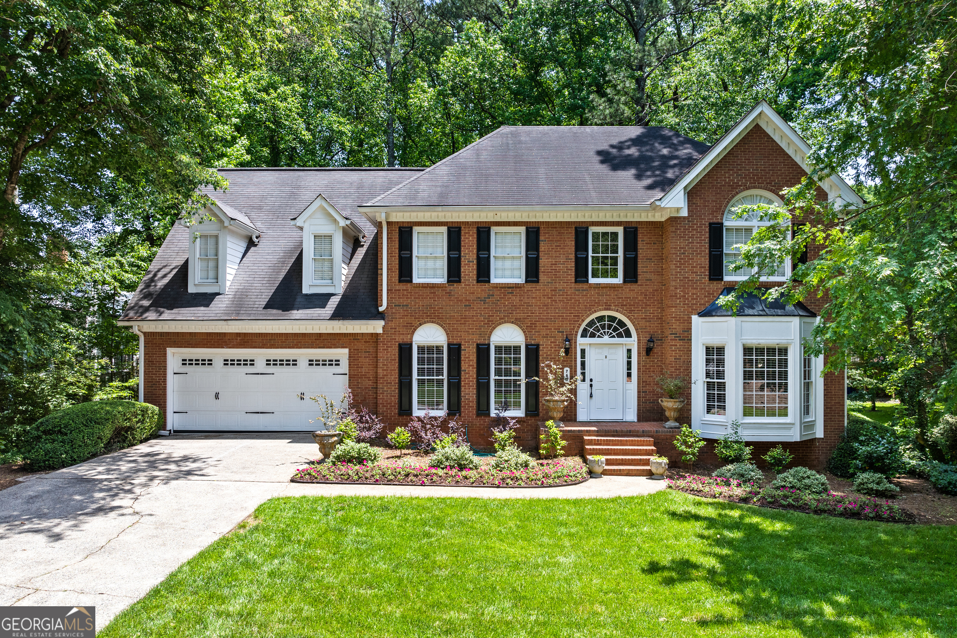 Luxury and timeless elegance define this exquisite all-brick estate nestled in the highly sought-after Old Paper Mill neighborhood. Set on over 0.43 acres of lush landscaped grounds, this home offers a rare and serene retreat. A tranquil stream meanders through the backyard, where a custom fire pit and tree-lined views create an inviting outdoor oasis-perfect for quiet mornings or lively evenings under the stars. Outdoor enthusiasts will love the proximity to Cochran Shoals Trail, just minutes away for walking, running, or biking along the Chattahoochee River. Inside, the grand two-story foyer welcomes you with warmth and sophistication. Refinished hardwood floors flow throughout the main level, complemented by fresh paint and refined brushed bronze finishes. The kitchen, thoughtfully refreshed in recent years, features gleaming granite countertops, stainless steel appliances, and a bright, airy aesthetic centered around a cozy breakfast nook. Formal living and dining rooms offer timeless spaces for entertaining, while a private library with custom built-ins provides a quiet escape. The expansive family room boasts rich wood-paneled walls, a stately fireplace, and seamless connection to the kitchen-ideal for gathering with loved ones. Upstairs, the elegant primary suite is a true retreat, showcasing a vaulted tray ceiling and spa-like bath complete with a skylight, soaking tub, dual vanities, and shower. Three additional oversized bedrooms and two well-appointed baths provide plenty of space for family and guests. The walk-out unfinished basement offers boundless potential-whether you envision a home gym, media room, or guest suite, it's a perfect canvas for your dream expansion. With charming curb appeal, mature trees, and a private, park-like setting, this home blends classic charm with thoughtful updates in a prestigious, established community. Come experience the lifestyle this special property has to offer. Schedule your private tour today!