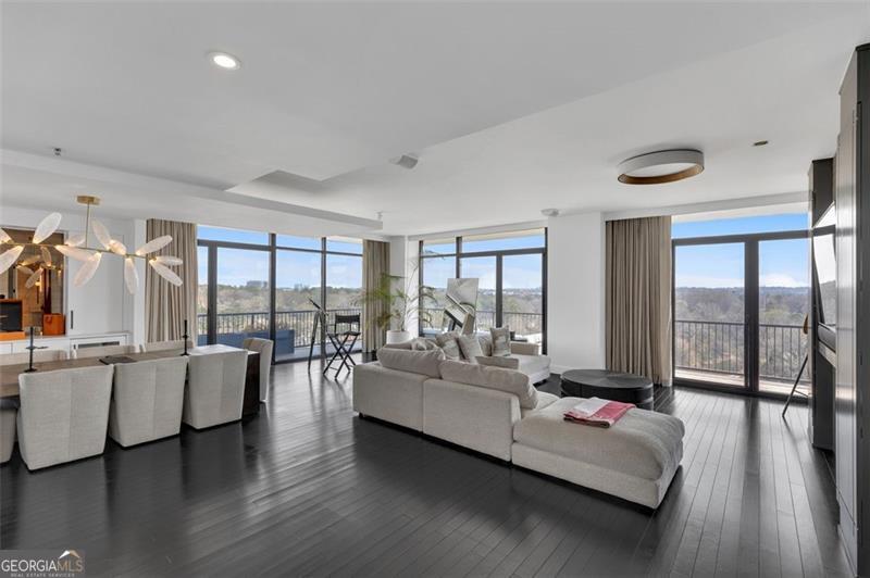 Nestled above the stunning Atlanta skyline, this expansive Astoria condominium epitomizes luxury living. Meticulously designed by the world-renowned Cooper Carry Architects, this residence is a true masterpiece of opulence in Buckhead, Atlanta. This rare, quiet end unit faces East toward Peachtree Hills, offering protected views free from future development. Enjoy treetop vistas, Peachtree Creek, and two iconic skylines: Buckhead and Midtown/Downtown. Boasting spacious, open interiors with soaring 10-foot ceilings, The Astoria at The Aramore seamlessly combines the finest materials-brick, stone, and glass-creating a timeless and enduring exterior. With only 70 residences in total, The Astoria offers exclusivity, with just six homes on the 8th floor. This McKinley corner end unit, one of the few available, spans the entire length of the North facade and the rear, providing unobstructed, panoramic views from all three sides. The unit includes three expansive terraces totaling 523 additional square feet, including one that gracefully wraps around, perfect for outdoor living. The residence is bathed in natural light thanks to its floor-to-ceiling windows and doors, blending the indoor and outdoor spaces effortlessly. The panoramic views showcase the glamour of Buckhead to the north, the allure of Midtown to the south, and the lush green canopy of Peachtree Hills framing it all. Few homes offer such iconic vistas of the Atlanta skyline. Completely renovated, this home combines sophistication with cutting-edge technology. Designed by Michael Habachy, the unit spans 3,167 square feet. The private primary suite, located on the east side of the unit, offers a tranquil retreat, while the west side features a second primary suite, a guest bedroom, and an office with views of Peachtree Road and Buckhead. The interior exudes modern elegance with sleek finishes, including upgraded fixtures, doors, and hardware. The home is fully equipped with Control4 home automation, allowing you to control lighting, music, heating/cooling, and security. All blinds and drapes are motorized for convenience, and the private office has been redesigned with Porcelanosa cabinetry for a sophisticated touch. For the culinary enthusiast, the kitchen is a dream. It features honed white stone counters and backsplash, custom-designed Blum cabinetry with integrated lighting, and premium Miele, Thermador, and SubZero appliances. The kitchen also includes island seating and built-in seating with storage running the length of the windows. The luxurious spa-inspired bathrooms offer ultimate relaxation, with handcrafted floating vanities, heated towel racks, heated floors, an oversized soaking tub with designer fixtures, a rain-steam shower with Steam Mist technology, and a separate water closet. Both walk-in closets are custom-designed by Porcelanosa. Residents of The Astoria enjoy an array of exclusive amenities, including a pool and separate spa with an outdoor fireplace, a covered grilling area, a wellness center, permanent green spaces, a pet walking area, 24-hour concierge service, and ample guest parking. This unit includes three secure, gated parking spaces. Located just moments from the BeltLine, parks, shopping, and renowned restaurants, this residence offers the perfect blend of luxury and convenience. Walk to the finest shops and dining in the neighborhood, and experience the pinnacle of Atlanta luxury living at The Astoria.