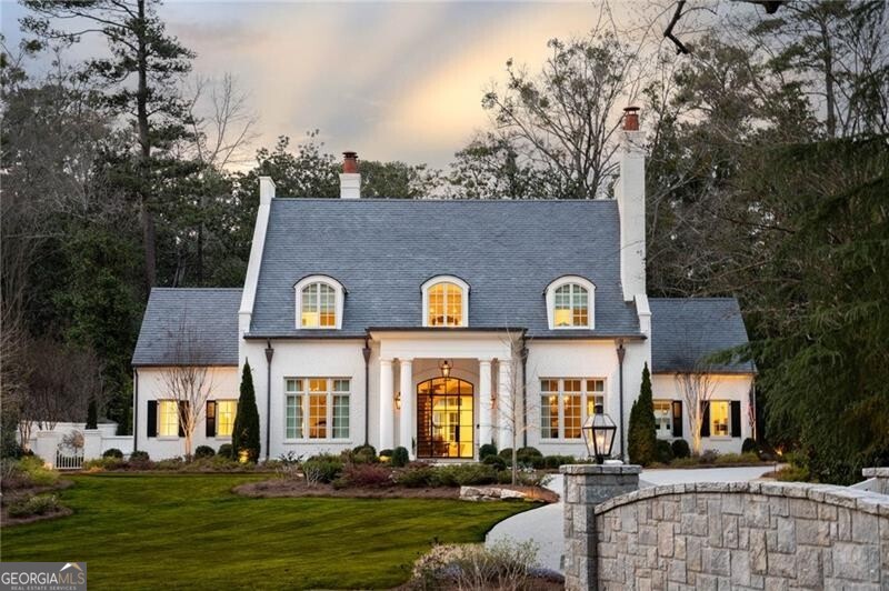 There was no detail overlooked in this stunning new construction in the coveted Tuxedo Park. Completed in 2021, this 8 bed, 7 full bath and 3 half bath home was the product of a collaboration between the Architects at Harrison Design and Builder Rick Fierer with Bildon Construction. The design gives the essence of old Atlanta with a traditional look and contemporary features, perfectly balancing elegance with an inviting and intimate feel. A double gated 24" custom masonry security fence guides you to the property tucked back on a beautiful flat lot. Custom steel doors lead you to the interior where you'll find soaring ceilings, gorgeous Venetian plaster, and 8" white oak floors all flooded with natural light. An open concept layout on the main level seamlessly connects the main living area, kitchen and sitting room which all feature floor to ceiling window walls overlooking the stunning outdoor living space and heated saltwater pool. The main floor living areas are adorned with Isokern masonry fireplaces with Francois custom limestone mantels and hearths and hand hewed custom whitewashed beams that add to the inviting nature of the home. The gourmet kitchen is perfection, lined with leathered Calcutta Gold on the large island and full height backsplash, Block and Chisel cabinetry, full Sub-Zero appliance package and an accompanying catering kitchen and butler's pantry. The main level primary bedroom features striking vaulted ceilings, private access to the outdoor living area and pool, and ensuite primary bath with honed and polished mystery white marble counters, shower cladding, handmade ceramic tile, heated floors and a steam shower. Entertaining is a must with the lower level featuring a fully equipped bar, state of the art theatre projection and a temperature-controlled wine room with a 1200 bottle capacity. A detached guest house just steps from the main residence would be the perfect in-law suite or private office. Additional enviable features include gourmet outdoor kitchen and built-in grill area, elevator access to all three floors and fully automated smart house Lutron, Control4 integration, whole house water filtration, and Flologic.