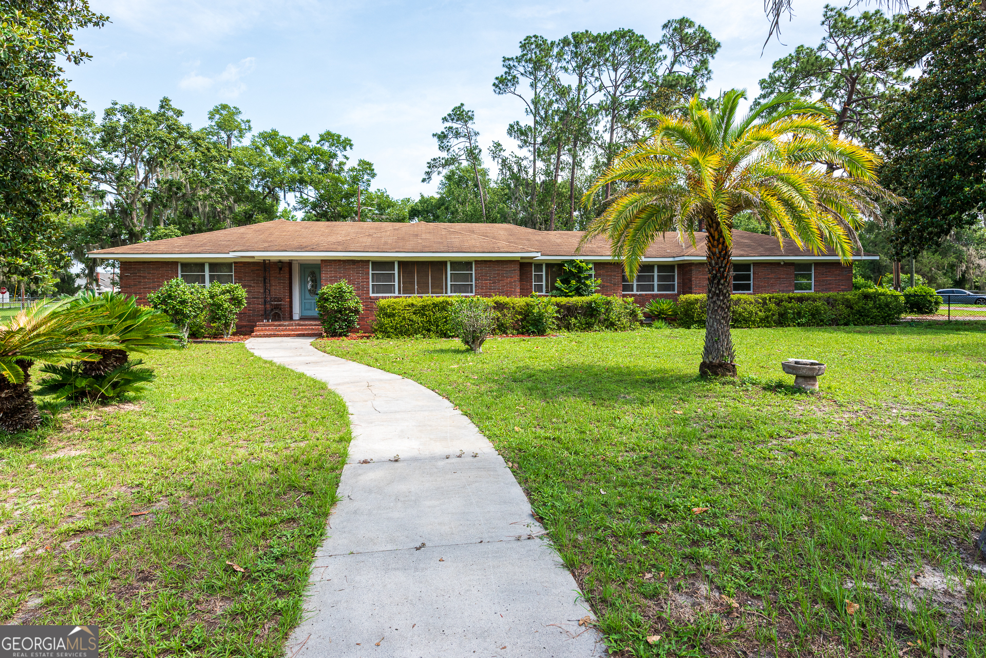 Own an entire block of Folkston with This Spacious Vintage Charmer! Situated on just over an acre, this classic 3-bedroom, 2-bath brick home offers 2,577 square feet of comfortable living and is just minutes from the heart of town! Inside, original hardwood floors flow throughout, leading to a spacious owner's suite perfect for unwinding, working, or relaxing. You'll also find a welcoming living room, a formal dining area ideal for hosting, a cozy kitchen, a versatile wood-accented office/bonus room, and a practical indoor laundry/mudroom. Outside, you'll love the fully fenced yard and large patio-perfect for pets, relaxing, or storing recreational gear. With mature Magnolia trees and lush landscaping, the backyard offers exceptional privacy and a peaceful setting. No distractions-just quiet living with room to grow! Schedule a showing today!