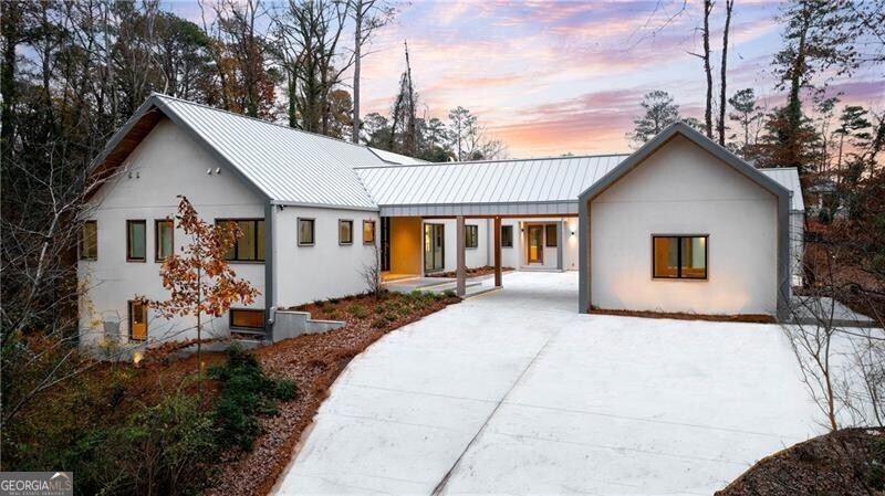 Perched on a serene 1.7-acre estate lot, this newly constructed residence represents the apex of luxury living. Inspired by Nordic modernism, its architecture captivates with dramatic gabled rooflines, a smooth stucco fa ade, and a sleek standing seam metal roof. The grand entrance, framed by striking steel doors, opens to a foyer that introduces the home's exquisite craftsmanship, including wide-plank white oak floors that flow throughout. The heart of the home is a soaring great room, where vaulted, wood-beamed ceilings and skylights bathe the space in natural light. Anchored by a two-sided fireplace, this expansive living area seamlessly integrates a family room and dining room. Oversized sliding glass doors blur the line between indoors and out, revealing a resort-style infinity-edge pool, spa, and an expansive terrace set against the tranquility of lush canopy views. A showpiece for entertaining, the open-concept kitchen centers around a statement island, complemented by custom cabinetry, a spacious walk-in pantry, and a professional-grade Sub-Zero and Wolf appliance suite. Thoughtfully designed for one-level living, the main floor features a magnificent primary suite with vaulted ceilings, jumbo sliding doors to a private terrace, and direct access to the outdoor living spaces. The spa-inspired bathroom exudes opulence, offering dual vanities, a freestanding soaking tub, a frameless glass shower, and large-format stone flooring. This level also includes a junior primary suite, two additional guest suites, formal and informal powder rooms, a generous laundry room, a mudroom, and a three-car garage. A detached auxiliary suite offers a private bedroom and bathroom, ideal for a home office, fitness studio, or guest accommodations. On the terrace level, an architectural staircase leads to expansive entertainment spaces, including a family room with a wet bar, a recreation room, and an additional guest bedroom with a full bathroom. Oversized windows throughout flood the interiors with natural light, enhancing the open, airy ambiance. Located in the heart of Buckhead, this architectural masterpiece is moments from Atlanta's premier private schools, fine dining, luxury shopping, and major highways.