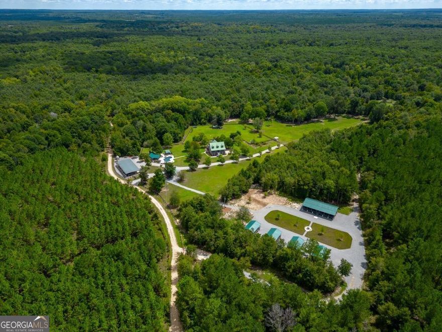 Greentop Plantation is an incredible 979 acre property along the banks of the Ocmulgee River in sought-after Wilcox County. From the top notch amenities to the game rich land & water features, Greentop Plantation will offer a first class recreational escape in these uncertain times.     The amenities here are truly first class, and will offer ultimate comfort & relaxation. The hand-hewn post and beam lodge boasts 4,072 square feet, 4 bedrooms and 4 baths. The wrap around porch, sunroom, & fine woodwork are some of the features that make this lodge hard to replicate in today's market(s). A large basement offers ample storage for hunting & fishing gear. A newly constructed pool house overlooking an incredible in-ground pool offers additional relaxation. A 40x90 equipment shelter allows for several tractors, ATVs, and additional equipment to be stored out of the weather. A large grain bin with built in auger is in place to assist with the whitetail feeding. A skinning shed is on site with walk-in cooler, as well as a complete brick BBQ pit. Lastly, around the corner from the main lodge area sits newly constructed guest cabins with a mini lodge for gathering & dining. The mini lodge offers a large common area with fireplace & commercial kitchen inside. In between the cabins & mini lodge is an outdoor fireplace area to gather around after days afield. The improvements here would be extremely difficult to construct in this day and time, however it is all ready to go for the new owner's family, friends, and/or clients.    Greentop Plantation boats just over 2.5 miles of Ocmulgee River frontage. River lands are becoming more & more sought after as the years go by. The fertile soil, game rich environment, healthy forests, and scenic views are what most people yearn for when looking for land. Greentop offers all of those attributes.     Recreational & Hunting  Greentop Plantation has been managed for whitetail deer using guidelines by the QDMA. As a result, there are 70+/- acres of strategically placed food plots scattered across the plantation. Miles of interior roads allow access to every plot & portion of Greentop. The roads have been recently rocked & the creek crossings have had new pipes installed, further enhancing the accessibility here. The duck hunting is outstanding, with several sloughs & ox bow lakes on site. The current owner is not a turkey hunter, but turkeys can be frequently seen riding through the property and the roosting & brooding habitat is evident. Hog hunting is a given along Georgia's river lands, and that is no exception here. The fishing along the Ocmulgee River is exceptional, known for having world class catfish, bass, and red breast. The oxbow lakes on the property also allow for fishing opportunities. There is a large gathering area overlooking the Ocmulgee River, which will offer a great spot for campouts and much more!     History  The history here is very intriguing. The Okmulgee Indians once inhabited the land & river where Greentop Plantation now resides.  The fertile river bottomland is what brought the Okmulgee Indians to this tract and those surrounding, but now this generation of land stewards are the ones who must care for and enjoy these same lands. Artifacts such as arrowheads, pottery, drills, marbles, & more have all been found by the current owners. The artifacts that still remain seemingly have no end, and there is much more to find over the years.