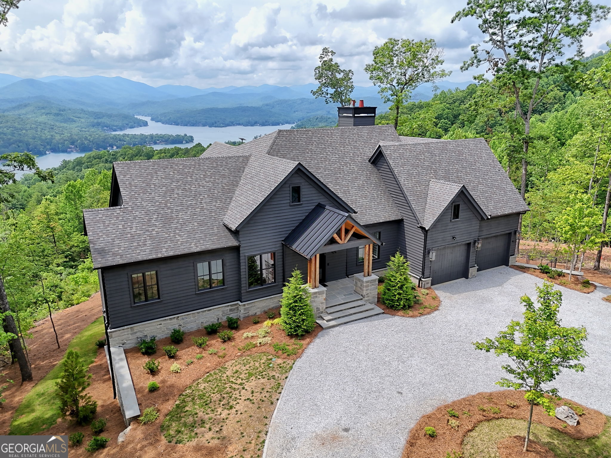 A masterpiece of modern luxury set amidst the highland serenity of Northeast Georgia and overlooking Lake Burton, 1572 Parker Hollifield Rd in Tiger stands as a rare architectural statement at 2,400 ft elevation. Completed in 2023, this 4,300 sq ft estate spans 1.17 acres and captures panoramic mountain views from nearly every room-an awe-inspiring backdrop for everyday living or an exceptional mountain escape. Each of the 5 meticulously designed bedrooms includes a private en-suite bath, enveloping guests in comfort and privacy. Striking floating staircases, expansive dual living areas, and seamless indoor-outdoor transitions set the stage for refined entertaining and quiet reflection alike. The gourmet kitchen is a culinary sanctuary with Wolf and Sub Zero appliances, custom cabinets, quartz countertops, dual dishwashers, and a Miele integrated espresso system. Overlooking majestic vistas, the heated terrace with its indoor/outdoor fireplace invites year-round al fresco gatherings. The great room offers sleek and sophisticated interiors with floor-to-ceiling walls of glass that frame epic views of Lake Burton and the surrounding mountains and all outfitted with Hunter Douglas Smart Shades. The private third-floor office retreat includes a wet bar and sweeping views that elevate remote work to a tranquil luxury. Outdoors, professionally landscaped grounds feature an iron-fenced dog yard, custom fire-pit, and plenty of parking with a wraparound driveway and attached oversized 2 car garage. Smart home technologies and security with Starlink connectivity ensure modern convenience in this natural setting. This home isn't just built-it's curated! This home is conveniently located 1.8 miles from Murray Cove Rd public boat ramp on Lake Burton and 5.5 miles from the Anchorage Marina and a 25 minute drive back to Downtown Clayton. An extraordinary offering available only by private appointment. Your elevated mountain lifestyle begins here.