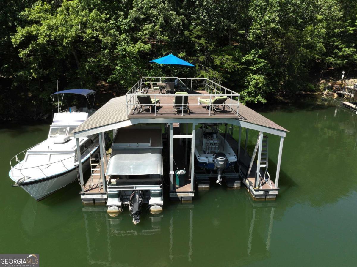 LAKE FRONT & DEEP WATER! This building lot offers so much more than others available. It is very convenient to so many things by boat and by car. Just a short boat ride to Pelican Pete's restaurant for dinner and live music! 15 minutes to downtown Gainesville for more restaurant choices and entertainment. Easy commute to Atlanta, North Georgia mountains and all of the little towns in between. The lot already has a very long asphalt driveway and a large storage barn with electric. Use it for a workshop, storage or for weekend camping until you build your dream lake home. The lot includes a 32' x 32' aluminum double slip dock with a party deck and a 6,000# boat lift. The dock is located on a wide deep cove with little boat traffic to disturb you as you relax on the party deck. The water depth is 20' at back of dock and 30' at front. THAT'S DEEP!!