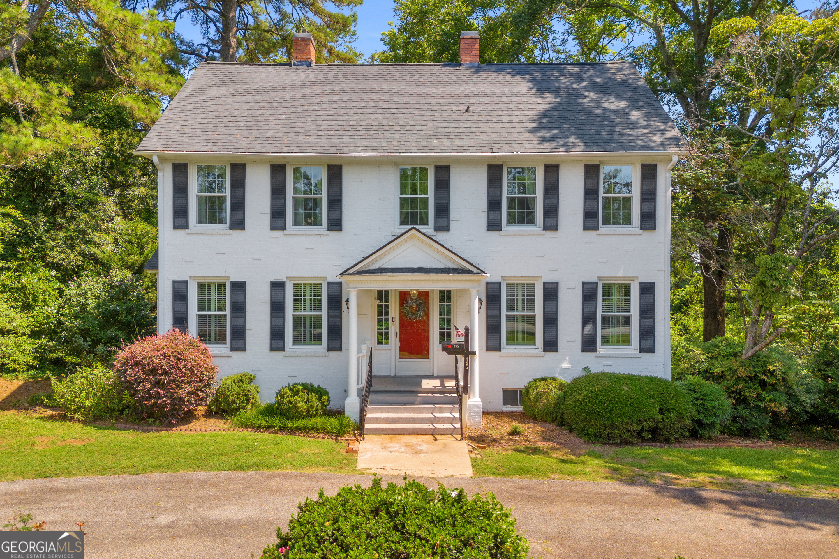 Timeless style and modern convenience come together in this beautifully maintained Colonial Revival home on a scenic 0.919-acre lot, just minutes from downtown Commerce. With 4 spacious bedrooms and 3 full baths, this classic two-story home offers two primary suites: one on the main level and another upstairs, providing flexibility for multi-generational living or guests. The stately exterior features painted white brick, black shutters, and a welcoming front porch that opens into a bright and inviting interior. You'll love the spacious layout, charming architectural details, and natural light throughout. A detached 2-car metal garage sits just behind the home, perfect for parking, storage, or hobbies. Surrounded by mature trees and lush landscaping, this property offers privacy, curb appeal, and convenient access to shopping, dining, and schools in Commerce. This is a rare opportunity to own a true Southern classic with room to grow and enjoy.