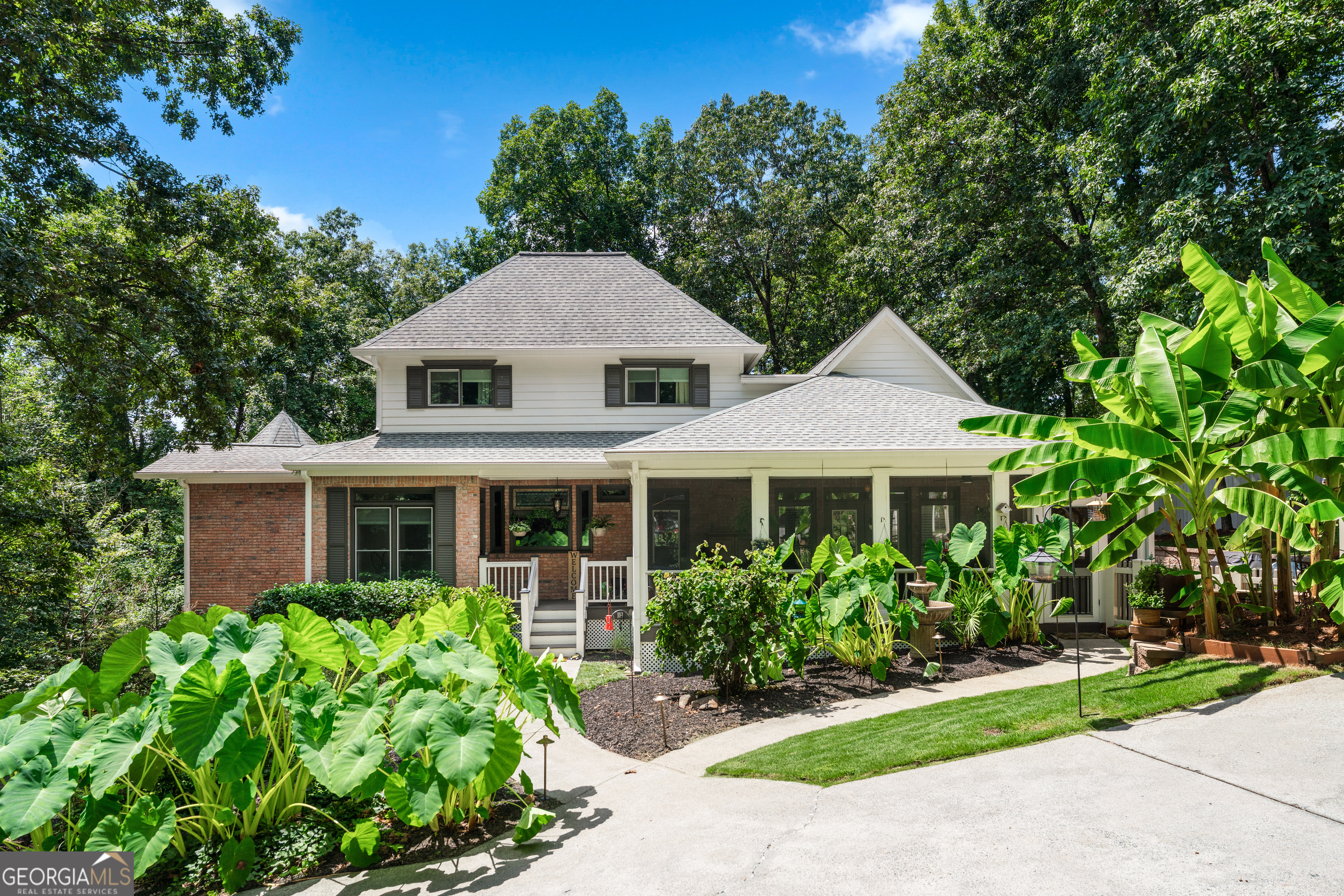 A Hidden Victorian Gem in East Cobb Where Privacy Meets Timeless Elegance. Tucked away behind a canopy of mature trees and completely invisible from the road, this enchanting Victorian-style retreat sits on 1.43 acres of pure serenity. Say goodbye to cookie-cutter homes and hello to a lifestyle defined by beauty, nature, and total privacy. Meander through an iron-gated stone courtyard past a koi pond, tropical landscaping, and a charming gazebo, creating your very own private oasis. The heart of the home is a chef's dream kitchen featuring cherry cabinetry, two copper sinks, stone counters, and top-tier KitchenAid commercial-grade appliances. The showstopping family room offers 14-foot vaulted ceilings with exposed beams, a stone fireplace, floor-to-ceiling windows, and a custom bar, perfect for cozy nights or grand entertaining. The main-level Owner's Suite invites relaxation with its spacious layout with renovated bathroom, while the formal living and dining rooms, plus dual screened porches, offer multiple spaces to unwind or gather. Upstairs, you'll find two generous bedrooms, a full bath, and a treetop-view loft. The basement offers a drive-under garage, a cement vault/storm shelter, workshop, finished flex space, and abundant storage. Love projects or guests? A rare 2-story, 4-car detached garage includes 850 SF of unfinished space upstairs already outfitted with utilities, ideal for a guest house or in-law suite. Surrounded by wooded views, mostly fenced yard, and East Cobb prestige, this home delivers the "WOW" factor at every turn, a true once-in-a-lifetime opportunity.