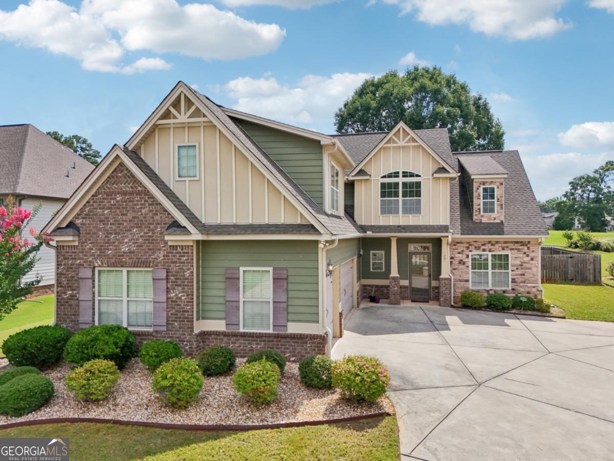 Welcome to this charming Craftsman-style home located in the desirable gated community of Madison Acres. Built by CAPSHAW Homes, this spacious property sits on a beautifully landscaped corner lot with a circular driveway and 3-car garage. The main level features hardwood flooring, a well-equipped kitchen with granite countertops, center island, separate cooktop, and double wall ovens. There's also a formal dining room and a primary suite on the main with a spa-like bathroom featuring a dual vanity, garden tub, and tiled shower with bench seating and dual shower heads. Upstairs offers three additional bedrooms and a spacious bonus room over the garage, perfect for a media room, playroom, or home office. Enjoy the fenced, shaded backyard and covered patio, ideal for outdoor relaxing or grilling. This home offers space, comfort, and the opportunity to make it your own-all within one of Henry County's most sought-after gated communities.