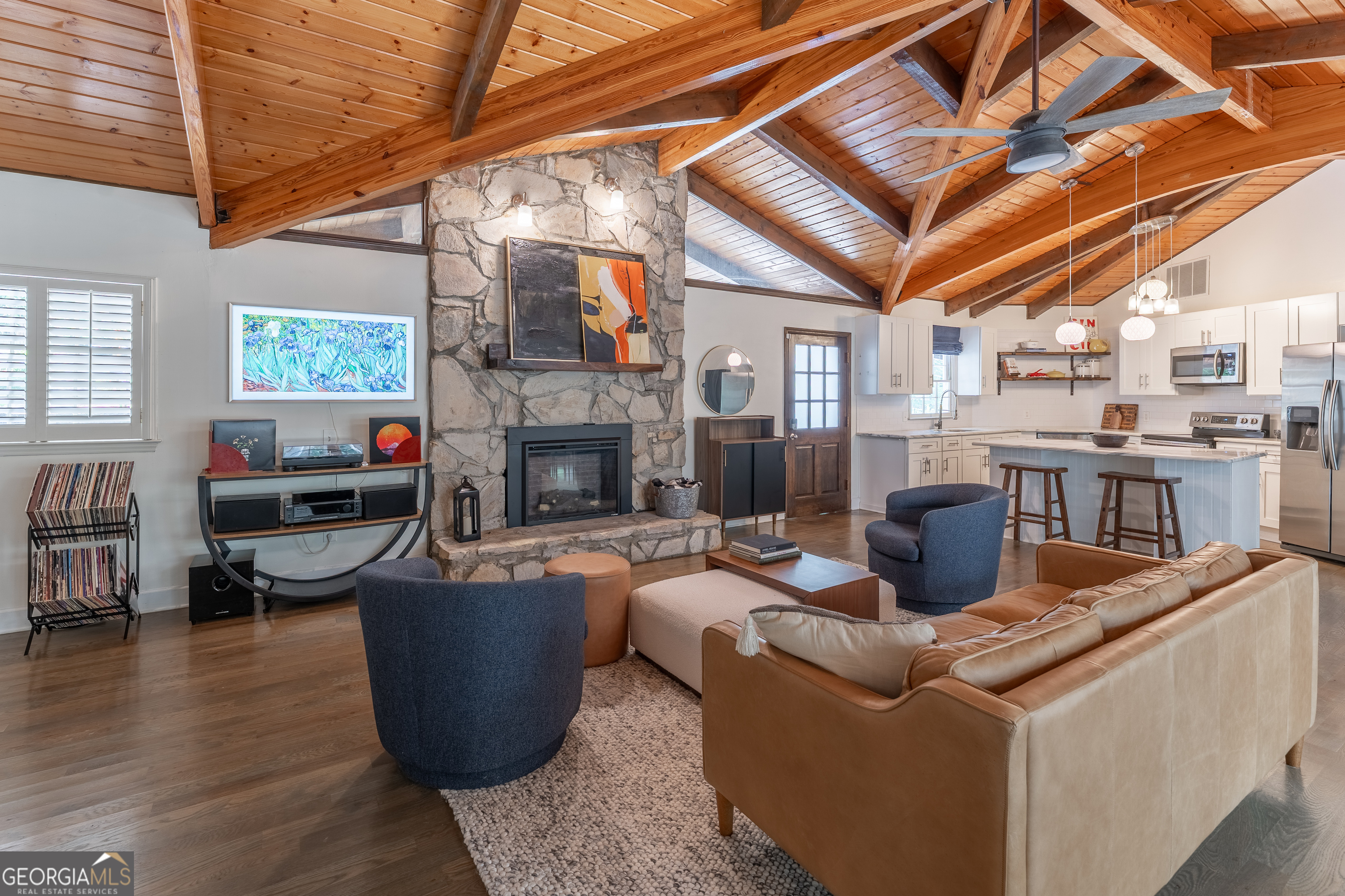 Mountain-modern style meets everyday comfort in this beautifully updated home just minutes from intown Atlanta and the heart of Smyrna. Featuring vaulted wood ceilings, an open-concept layout, and gleaming hardwood floors, this home is filled with natural light and designed for relaxed living. The main level offers a spacious vaulted family room with stone fireplace that flows into the renovated kitchen, complete with white cabinetry, stainless steel appliances, solid surface countertops, and an island. A full-length sunroom adds versatile space for dining, lounging, or a home office. The split-bedroom layout offers exceptional privacy, with each bedroom featuring its own full bath, vaulted wood ceiling, and walk-in closet. The terrace level mirrors the upper floor with a second living area with decorative stone fireplace, kitchenette, two additional bedrooms, full bath, and a second sunroom that opens to the backyard. Set on a wooded .33-acre lot, the outdoor space is perfect for entertaining or unwinding with a large deck, storage shed, and space for a firepit. Recent upgrades include a brand-new metal roof, fresh exterior paint, updated electrical, 2 year old HVAC systems, and 2 new water heaters. Whether you're looking for a serene place to call home or a unique layout for multigenerational living, this property delivers space, style, and privacy. Don't miss this one-of-a-kind retreat-schedule your private tour today!